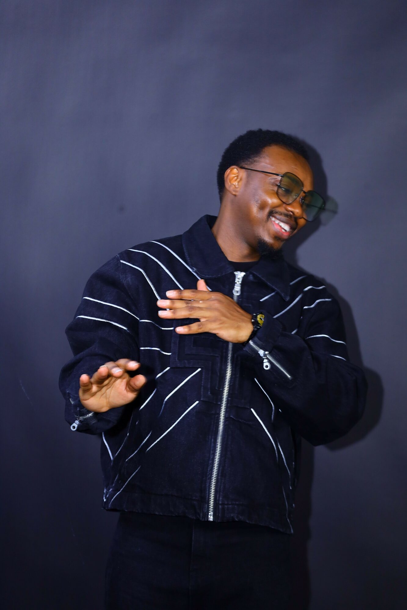 Person lying on the ground, wearing glasses and a striped jacket, appears to be laughing or smiling.