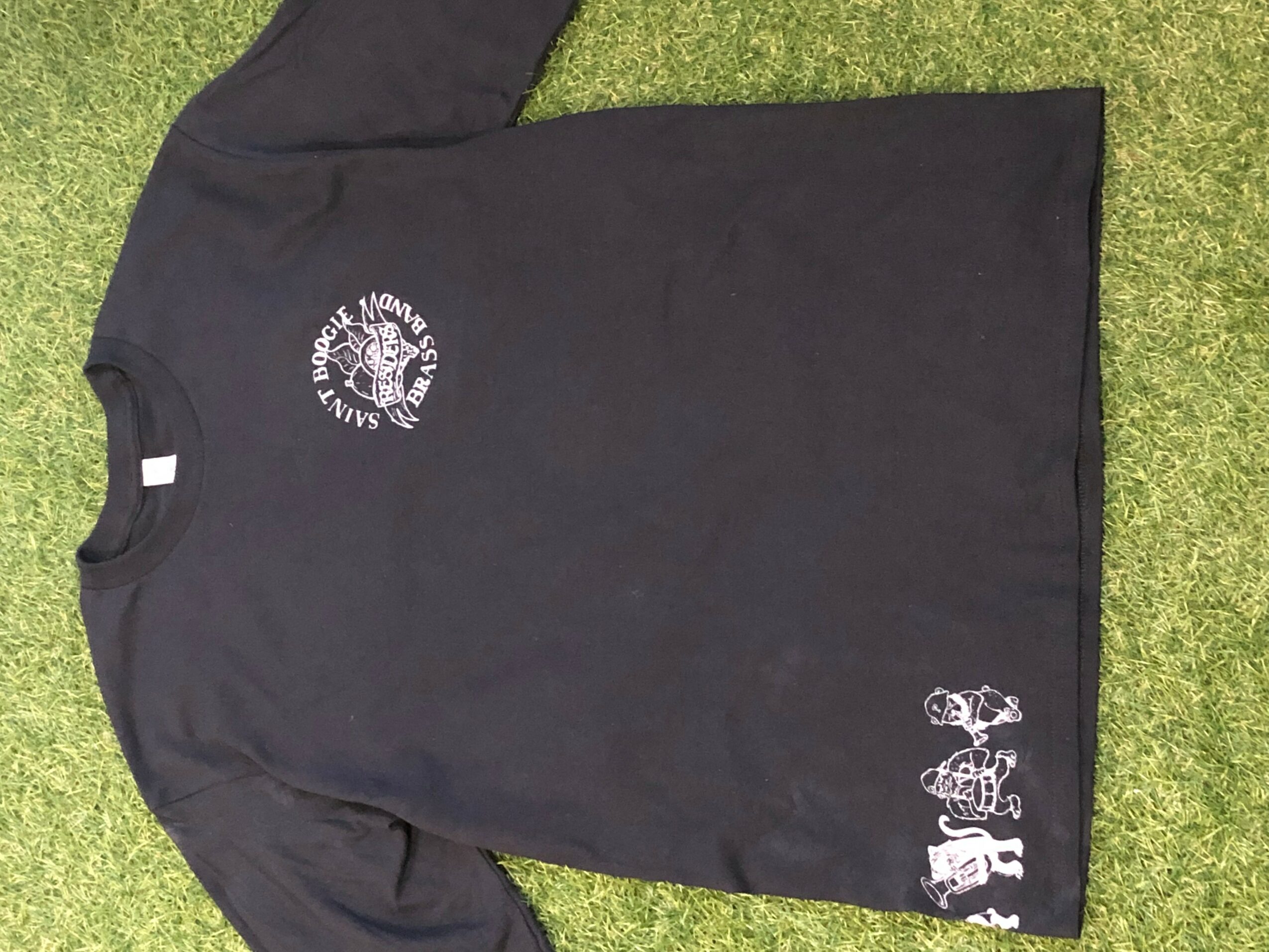 Black T-shirt with white text and graphics on a grassy surface, displayed sideways.