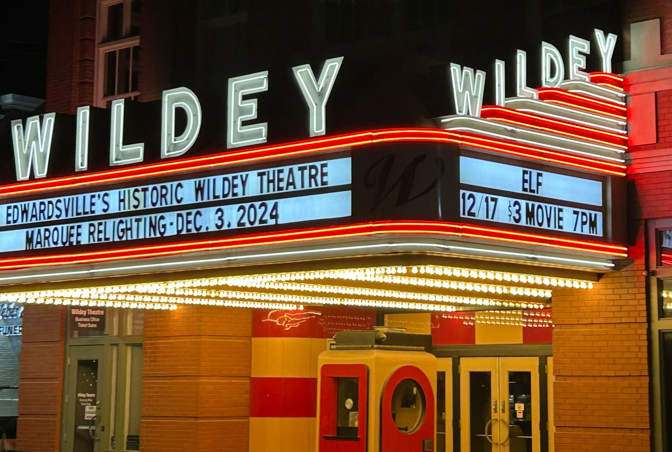 The marquee of the Wildery Theatre displays show information and bright lights, with the theater's name in large illuminated letters.