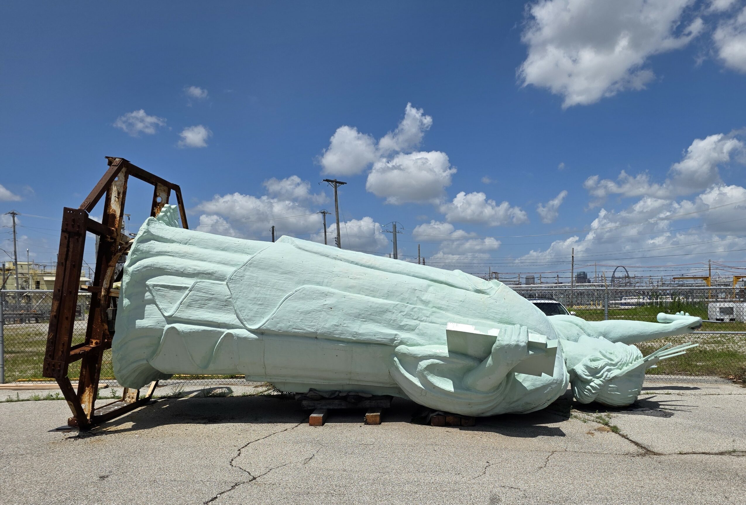 Fallen large inflatable structure on the ground with a blue sky and clouds in the background.