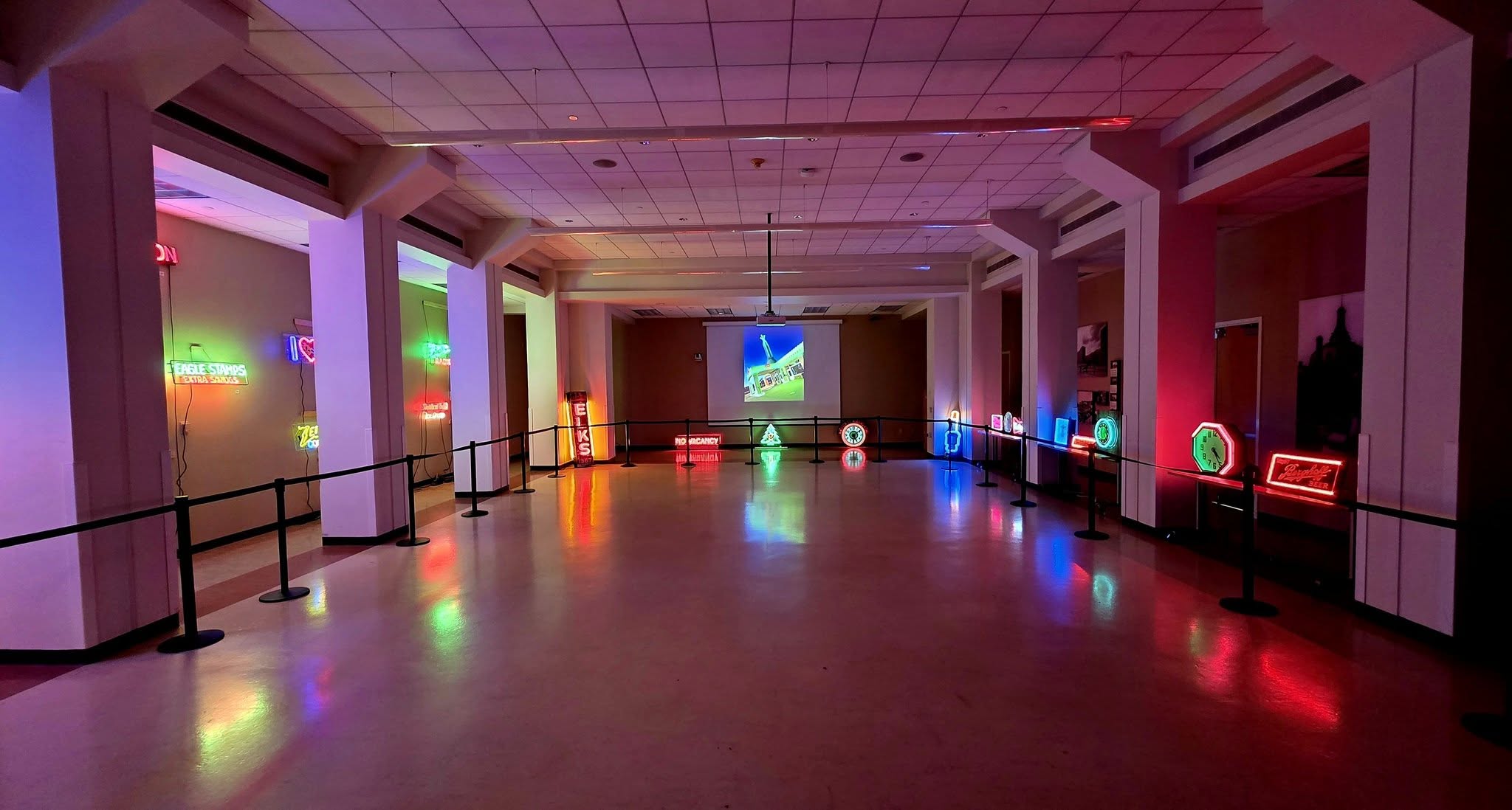 Empty room with colorful neon lights and reflections on the floor, decorated with neon signs and illuminated objects.