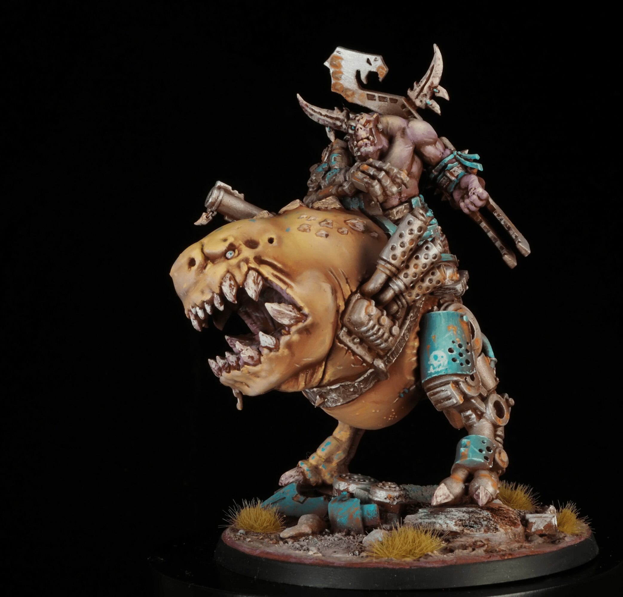 A detailed miniature figure of a warrior riding a large, fierce dinosaur with an open mouth, set on a base with grass and rocks.