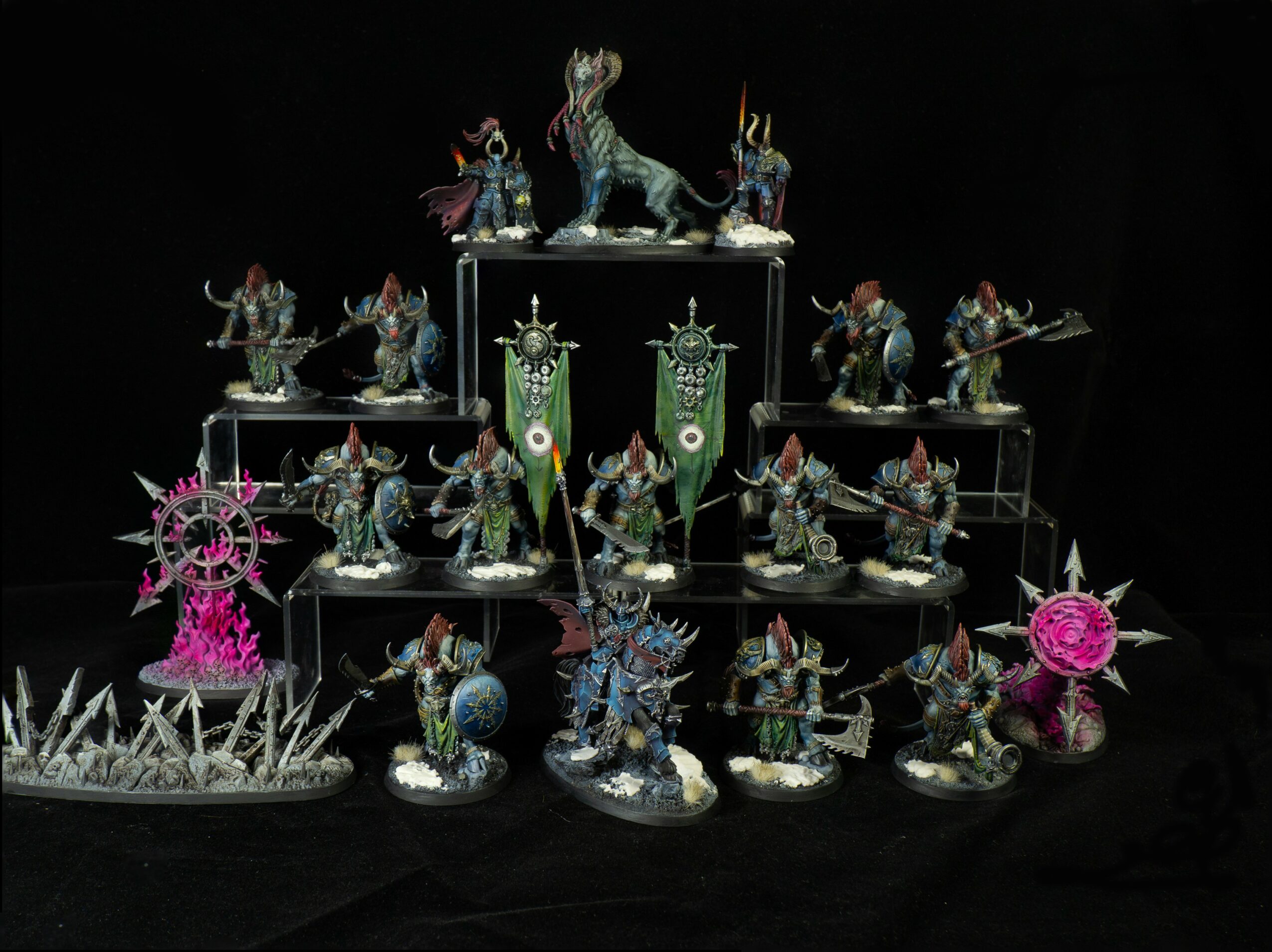 Collection of detailed fantasy miniatures with mythical creatures and characters, arranged on black background, including a large central creature and various figures.