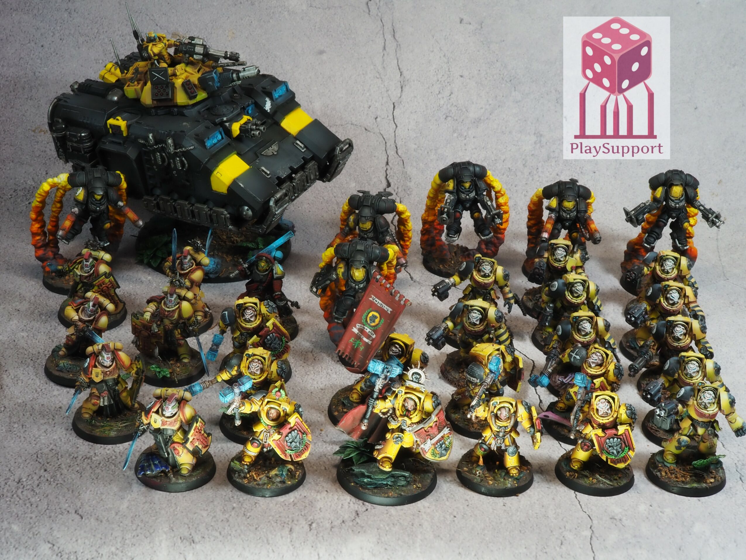 Group of miniature figures and a vehicle, painted in yellow and black, arranged on a surface.
