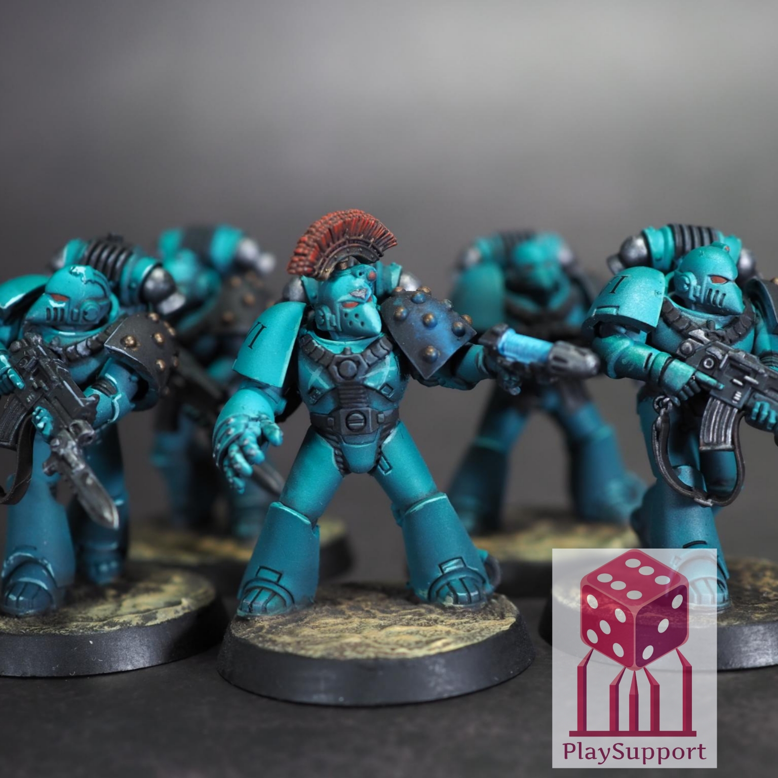 Group of blue armored miniature soldiers with one central figure holding a gun, on round bases, against a gray background.