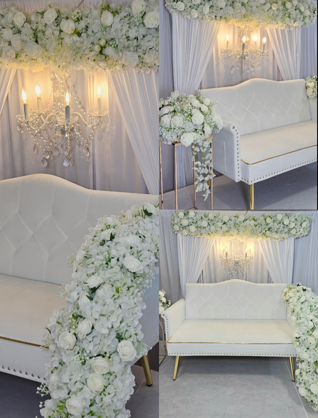 Elegant white sofa with floral arrangements and draped curtains, illuminated by chandeliers and wall sconces, in a decorated setting.