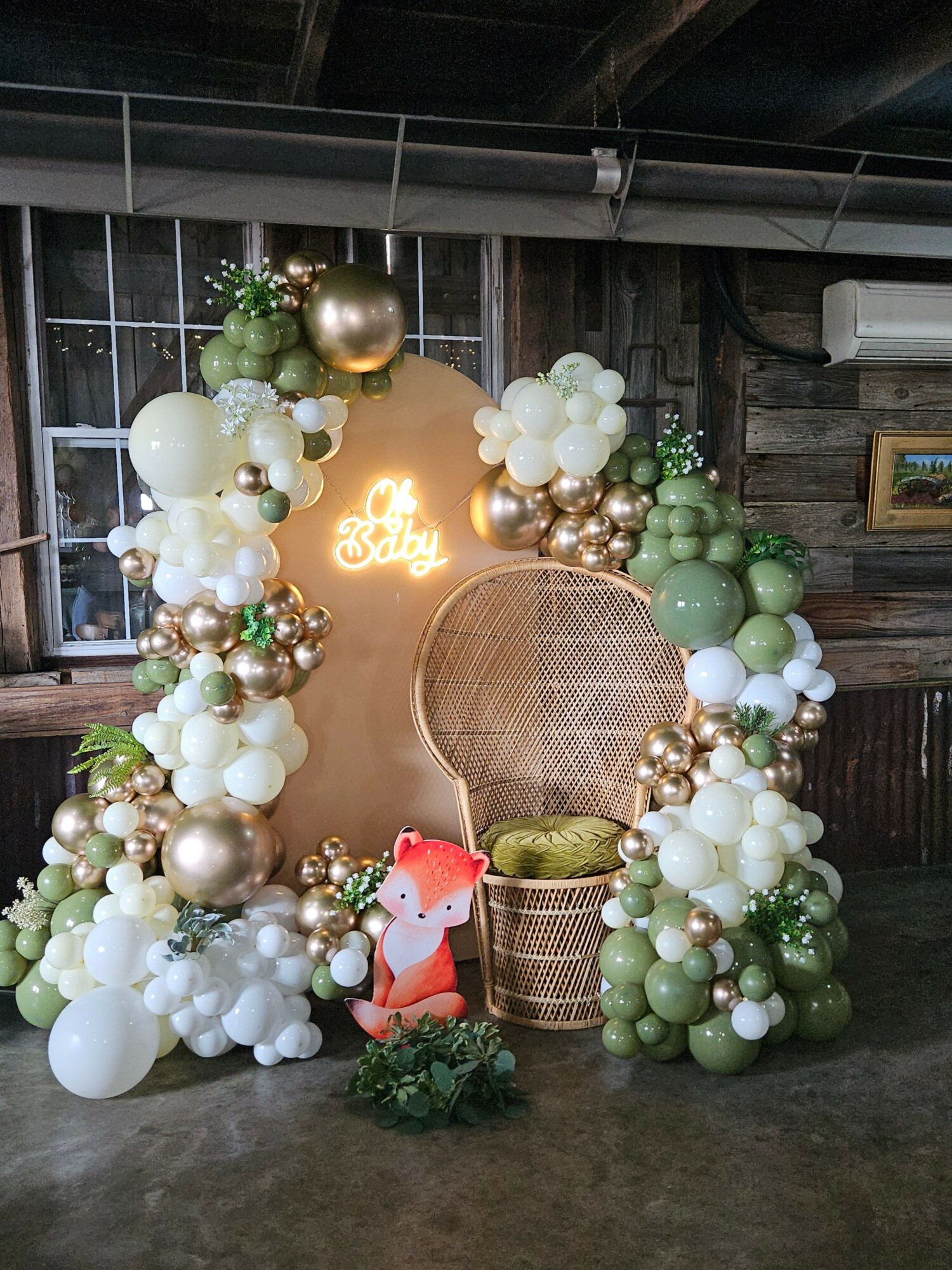 Decorative arrangement with balloons, a neon sign, and a small figure, set against a wooden background.