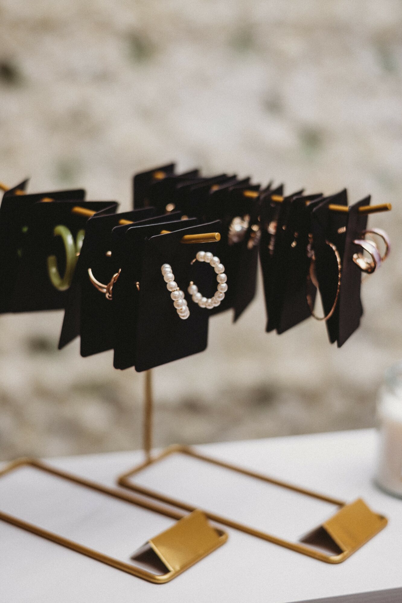 Black display cards with jewelry, including rings and earrings, on a stand against a blurred background.