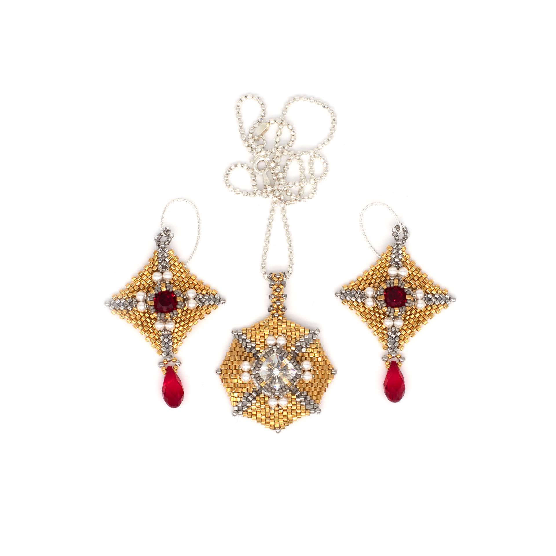 Jewelry set with a pendant and matching earrings featuring gold, white, and red stones, and a chain, on a white background.