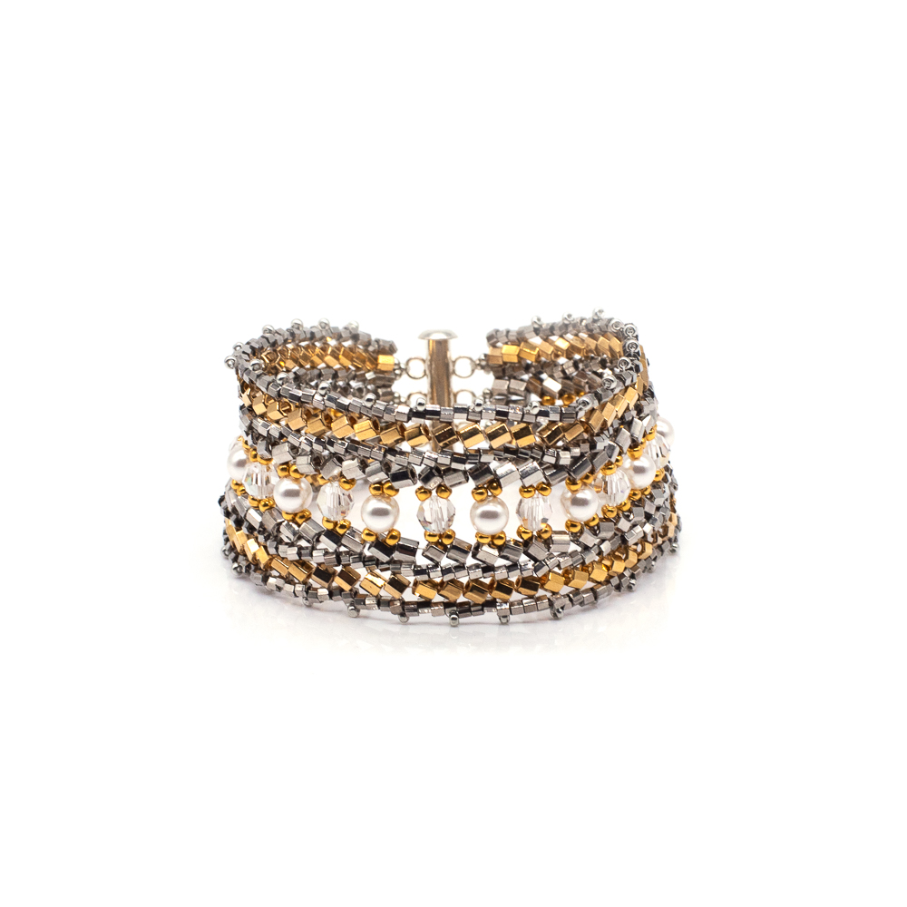 Multiple layered metallic bracelets with gold, silver, and black elements, stacked together, on a white background.