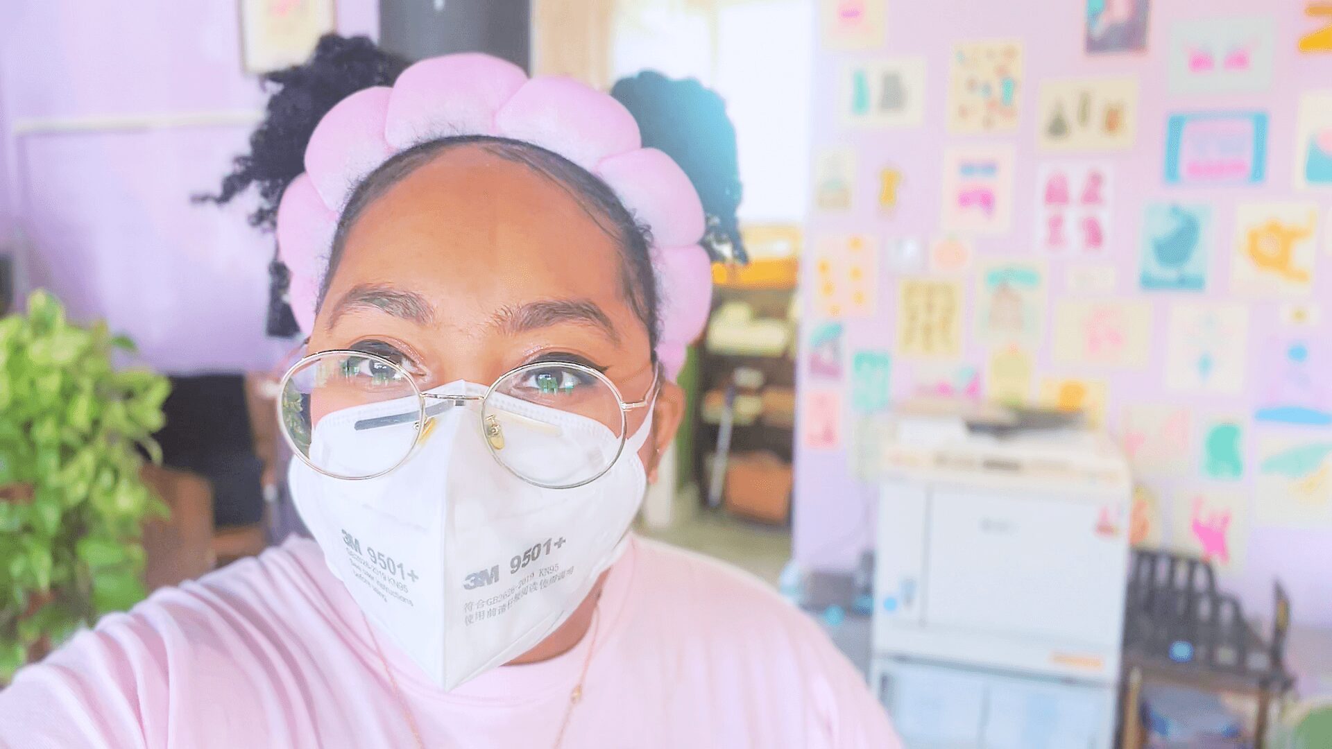 Person wearing glasses and a face mask, with a colorful classroom background.