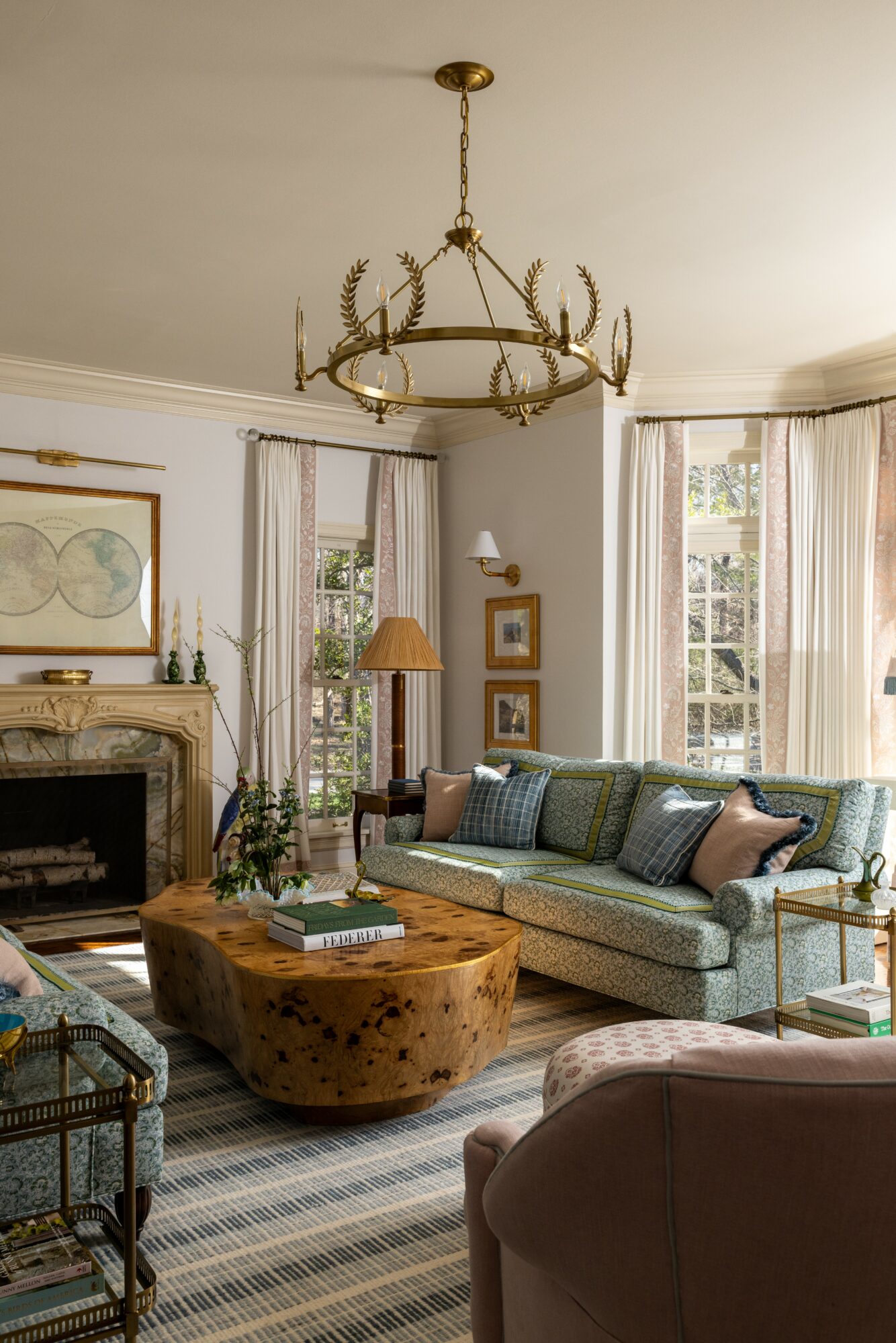 Living room with a chandelier, large windows, a sofa, a wooden coffee table, and a fireplace.