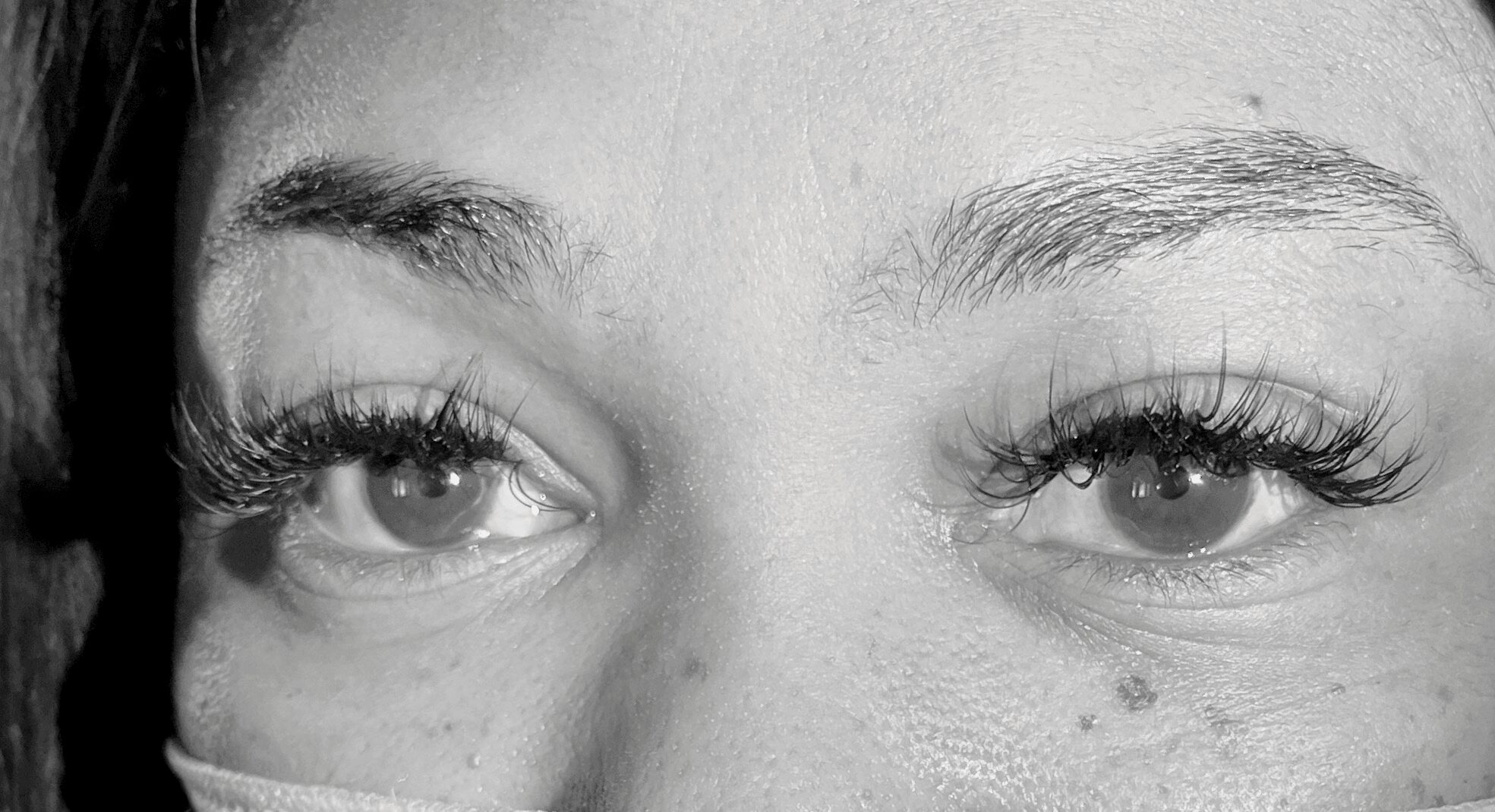 Close-up of a person's eyes and eyebrows, with visible eyelashes and skin texture.