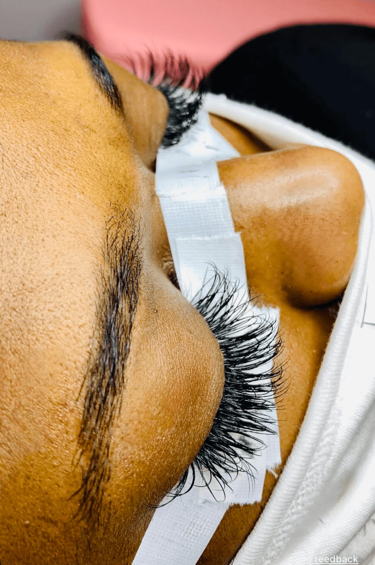 Close-up of a person's face with closed eyes, long eyelashes, and a white eye patch, lying down.