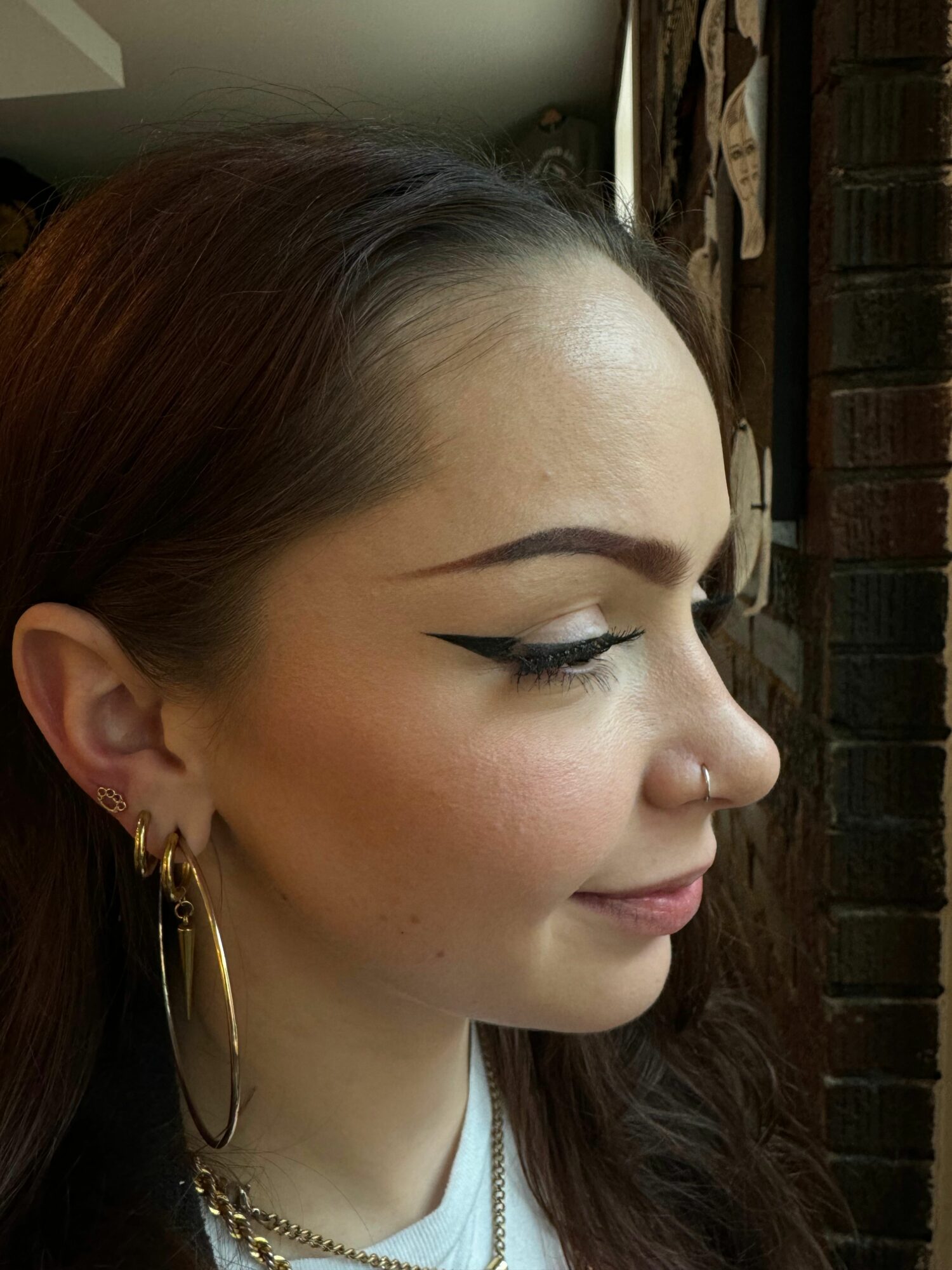 Side profile of a woman with makeup, earrings, and a necklace, lying down with eyes closed.