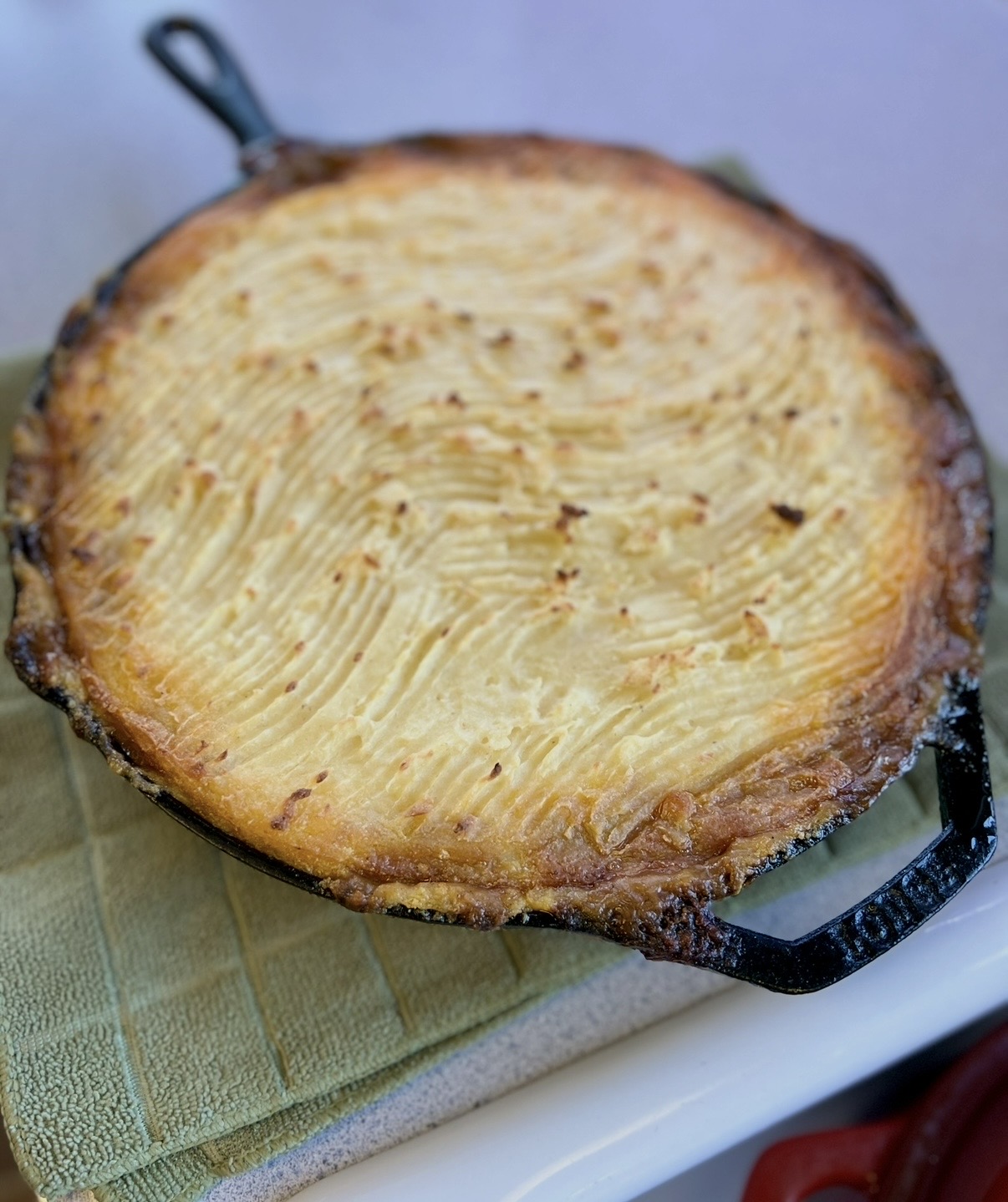 A round baked dish with a golden crust and ridged surface, placed on a cloth-covered surface.