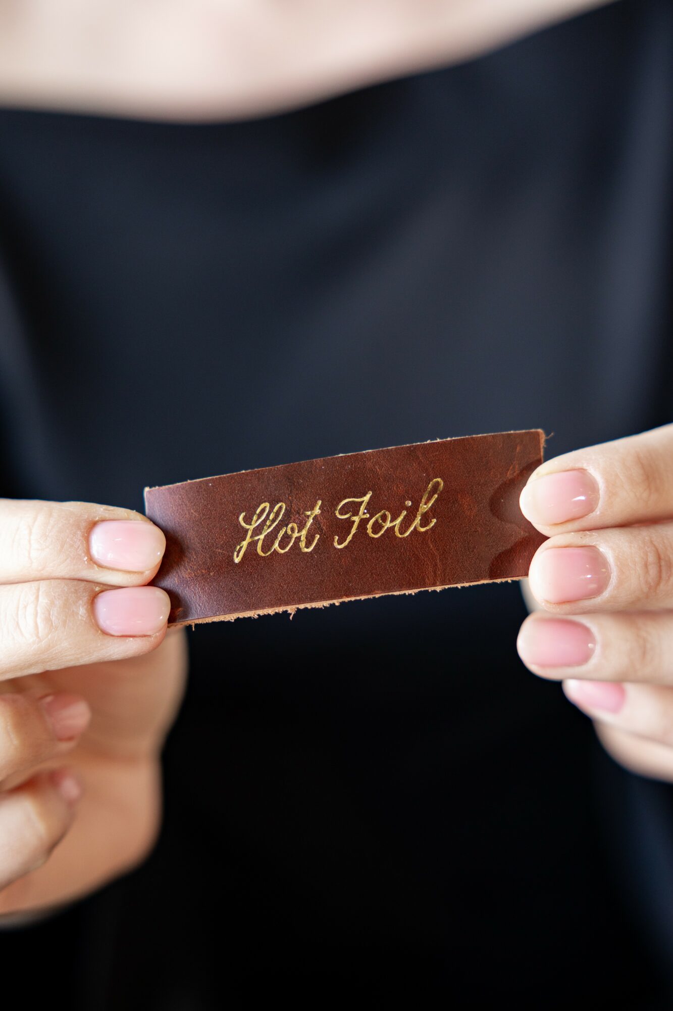 Person holding a brown leather card with gold cursive text reading 'Hot Foul'.
