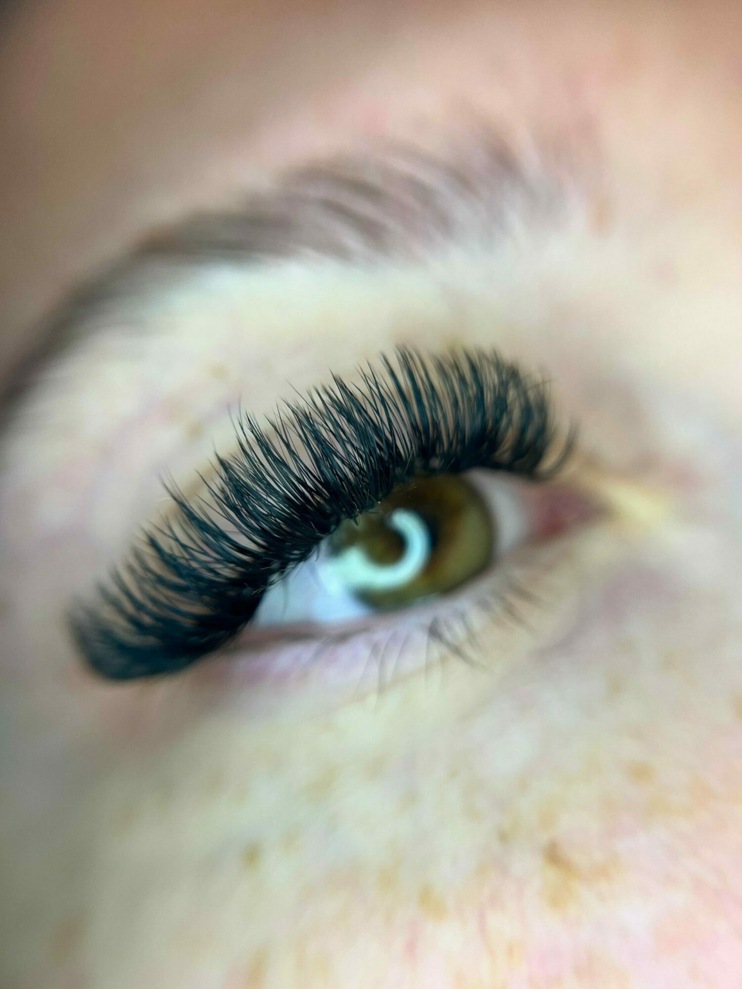 Close-up of a person's eye with long, dark eyelashes and light-colored skin around the eye.