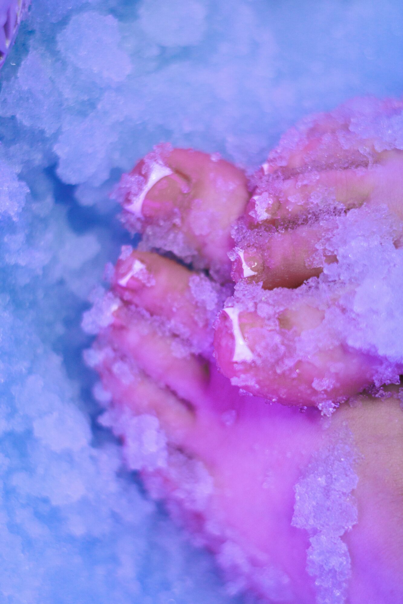 Close-up of a hand with pinkish skin, surrounded by white crystalline salt, against a blue background.