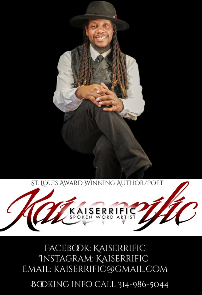 Person with long dreadlocks, wearing a hat, white shirt, and vest, sitting with crossed legs, smiling, against black background.