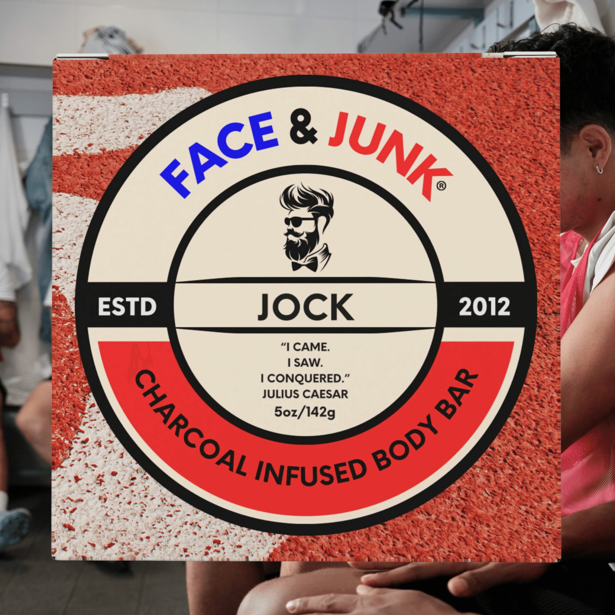 Person holding a circular sign with text and a logo, partially visible. Background shows a person in a white coat and another person in red. The sign has a red, black, and white color scheme with text about a charcoal-infused body bar.