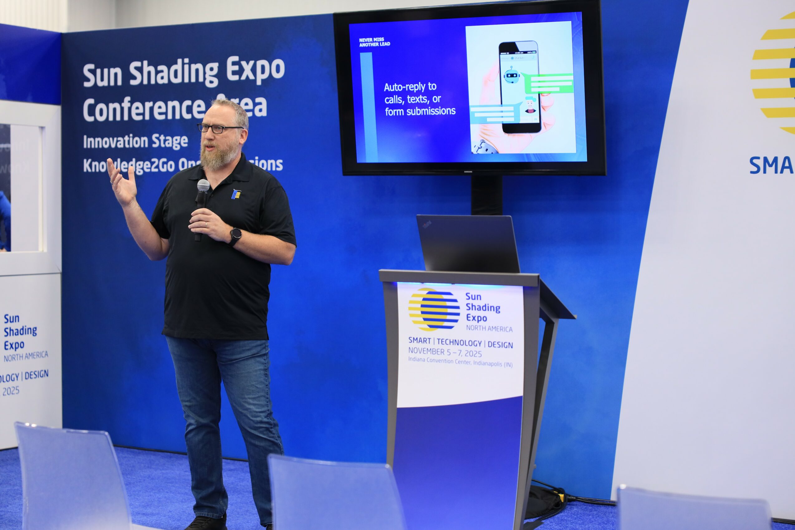 Man speaking at Sun Shading Expo Conference, with a presentation slide on a screen behind him, blue background, and a podium.