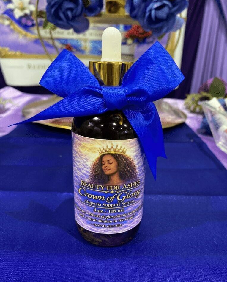 Bottle with a blue ribbon bow, candle, and floral decorations in the background.