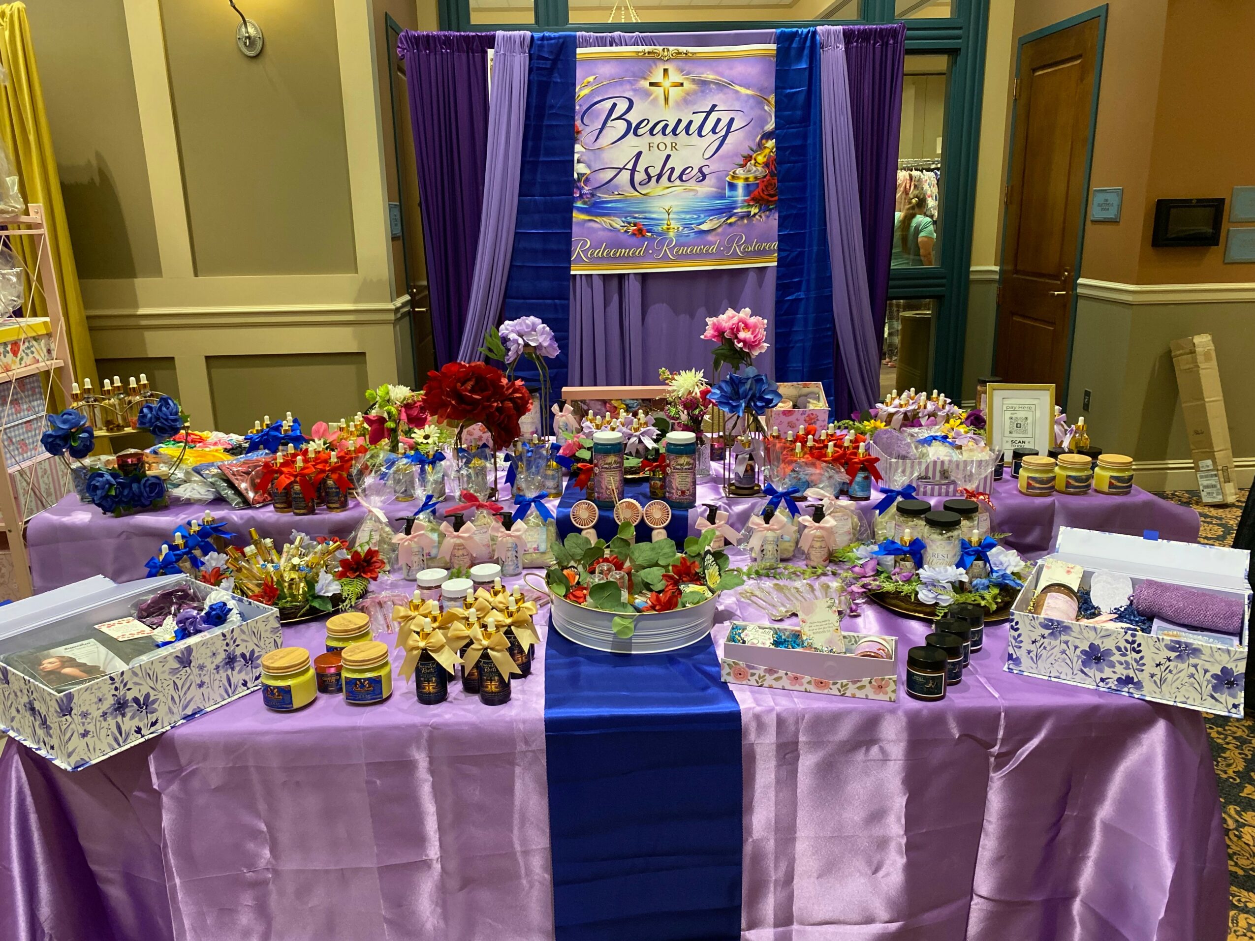 Table with colorful desserts, flowers, and decorations, with a banner reading 'Beauty & Ashes' in the background.