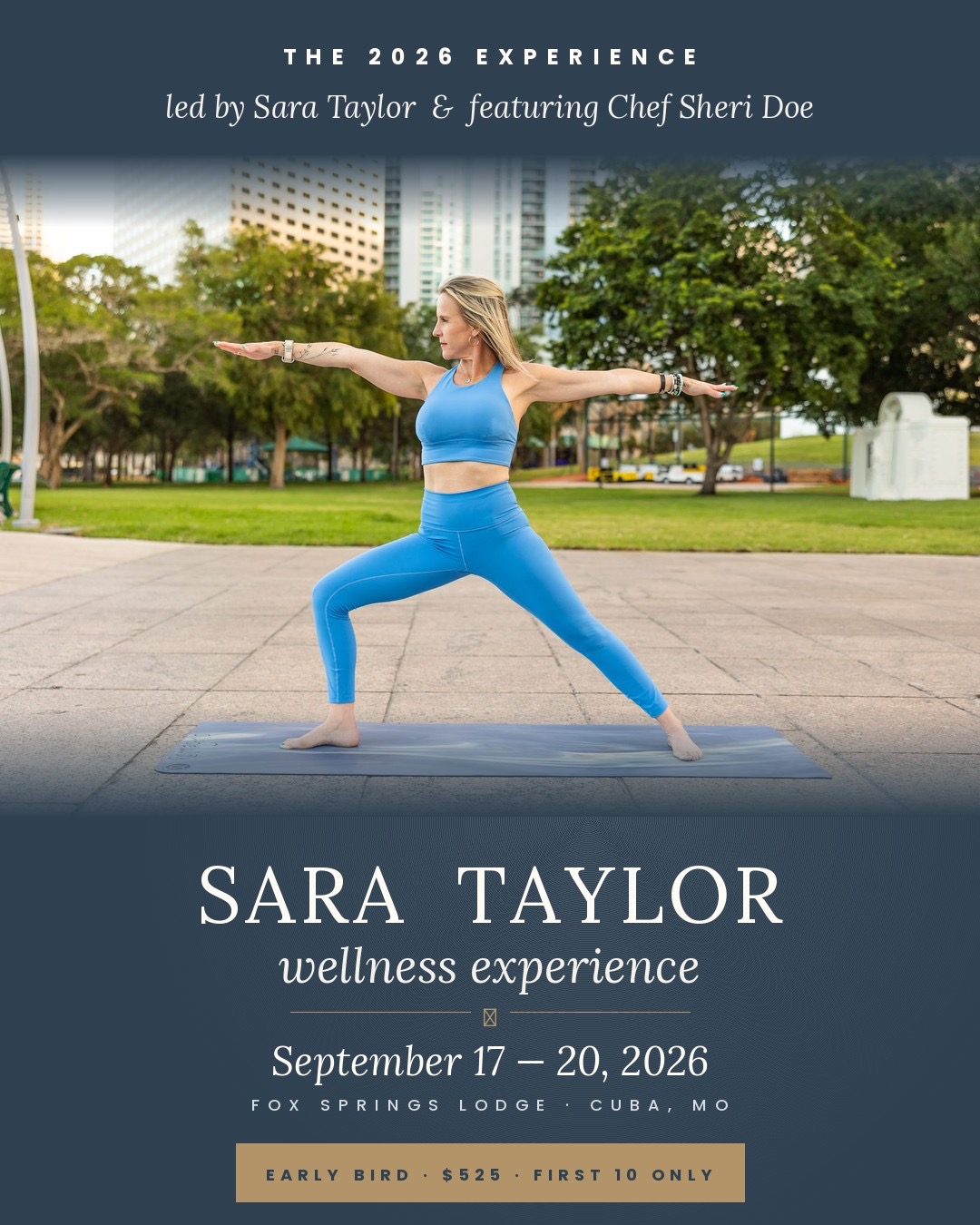 Woman practicing yoga outdoors in a park with trees and buildings in the background, wearing blue athletic clothing, arms extended.