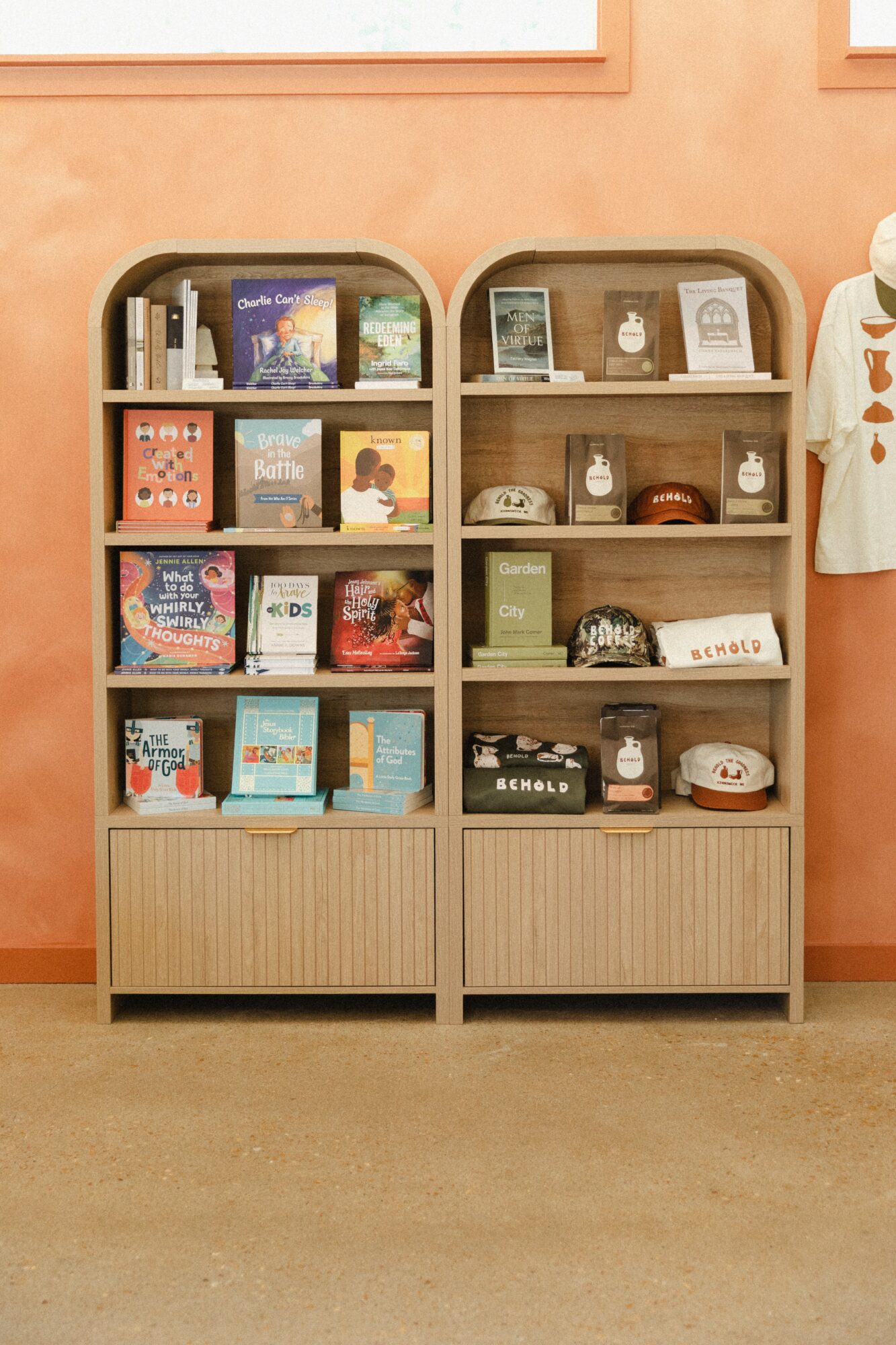 Two bookshelves filled with books, jars, and decorative items against a peach-colored wall.