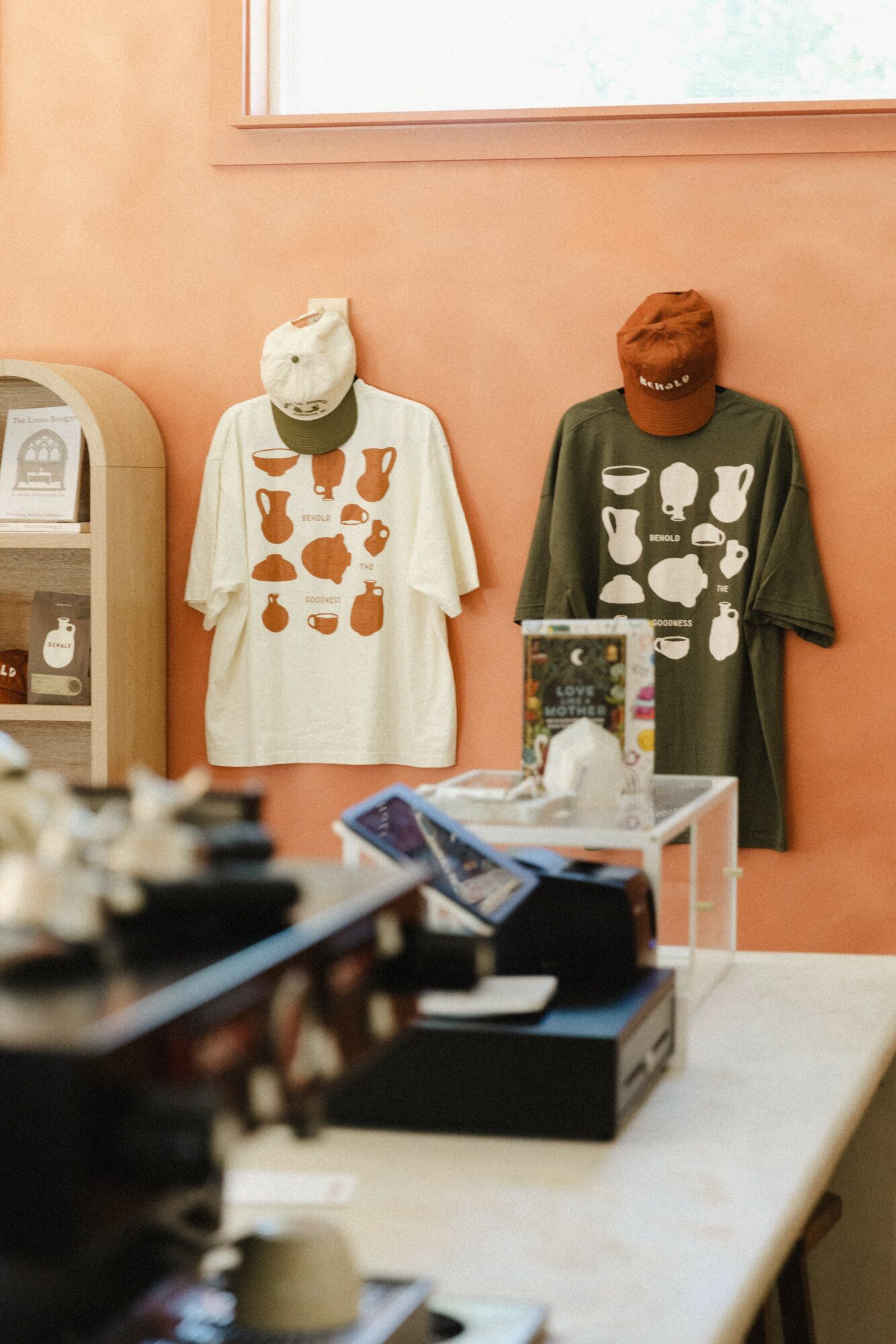 Two mannequins wearing animal-themed costumes and masks, displayed against a peach-colored wall with a window above, in a store or display area.
