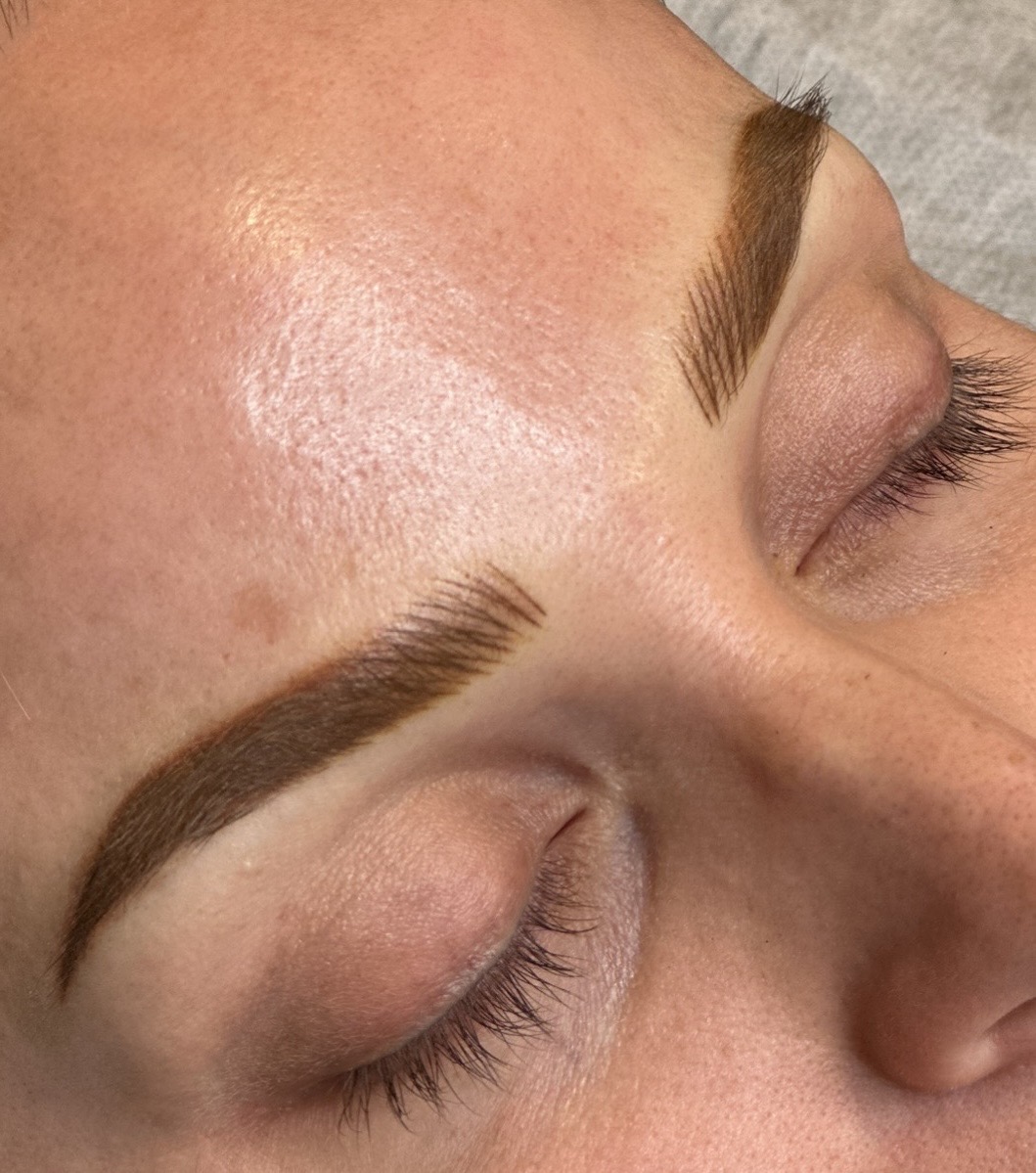 Close-up of a person's face with closed eyes, showing well-groomed eyebrows and smooth skin.