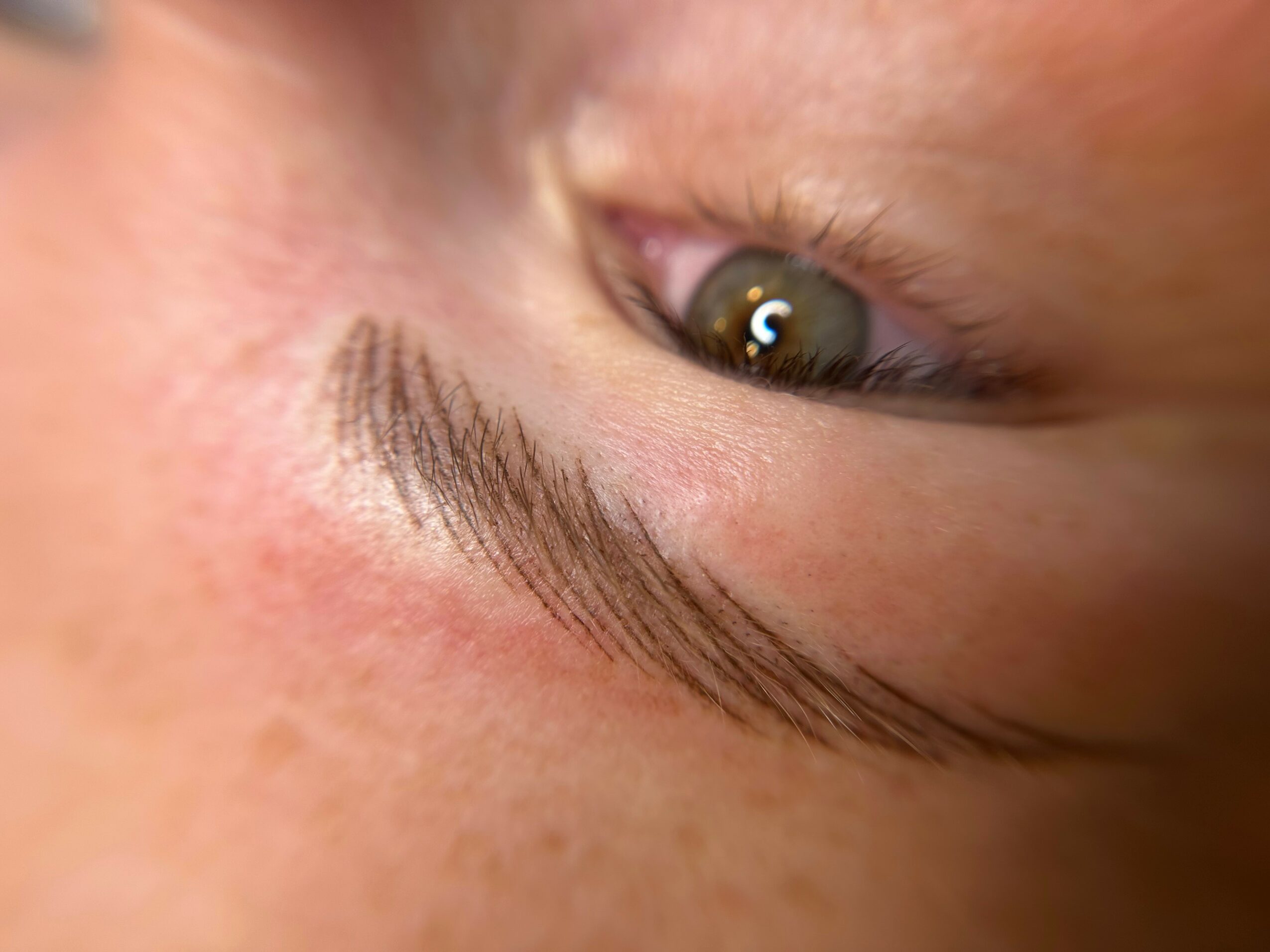Close-up of a person's eye and eyebrow, showing detailed skin texture and eye color.