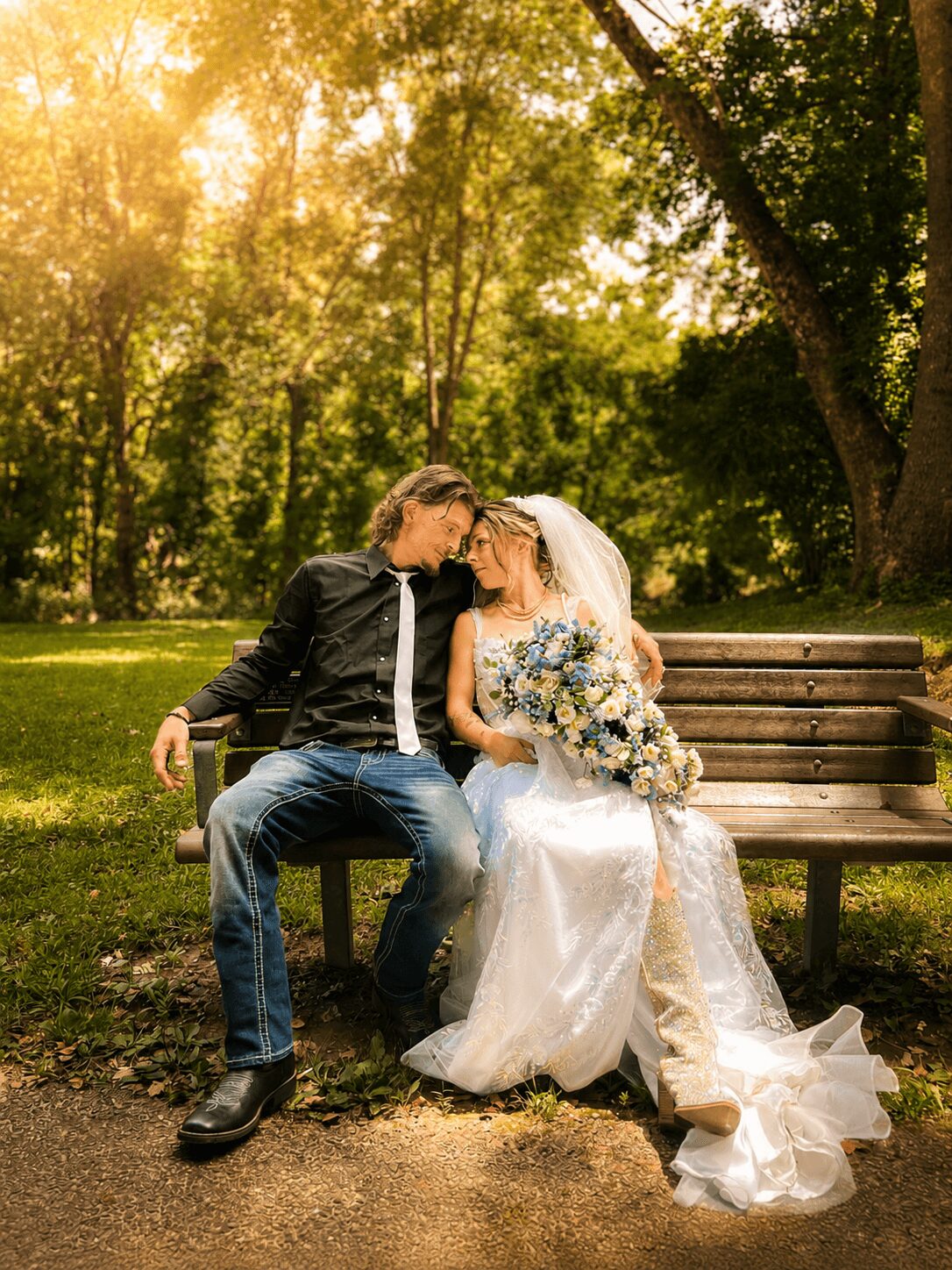 A couple sits on a park bench, embracing, with sunlight filtering through trees in the background.