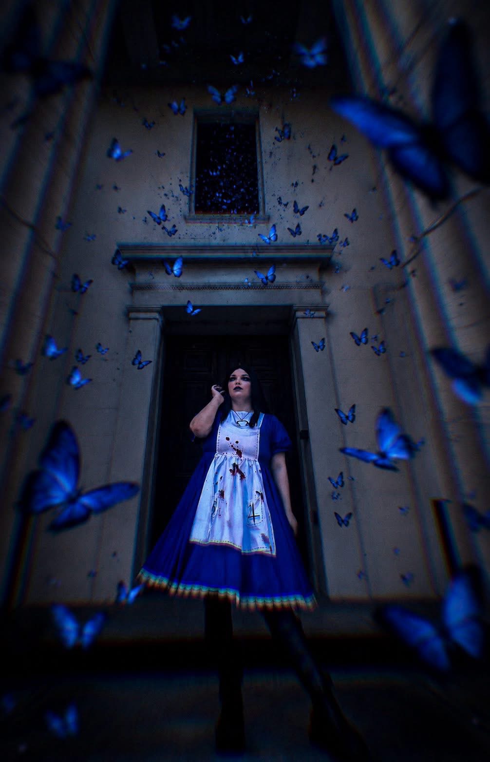 Person in a dress standing in front of a building entrance surrounded by blue butterflies flying around.