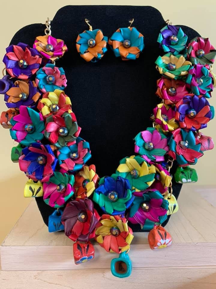 Colorful flower-shaped jewelry set with earrings and a necklace displayed on a black stand.