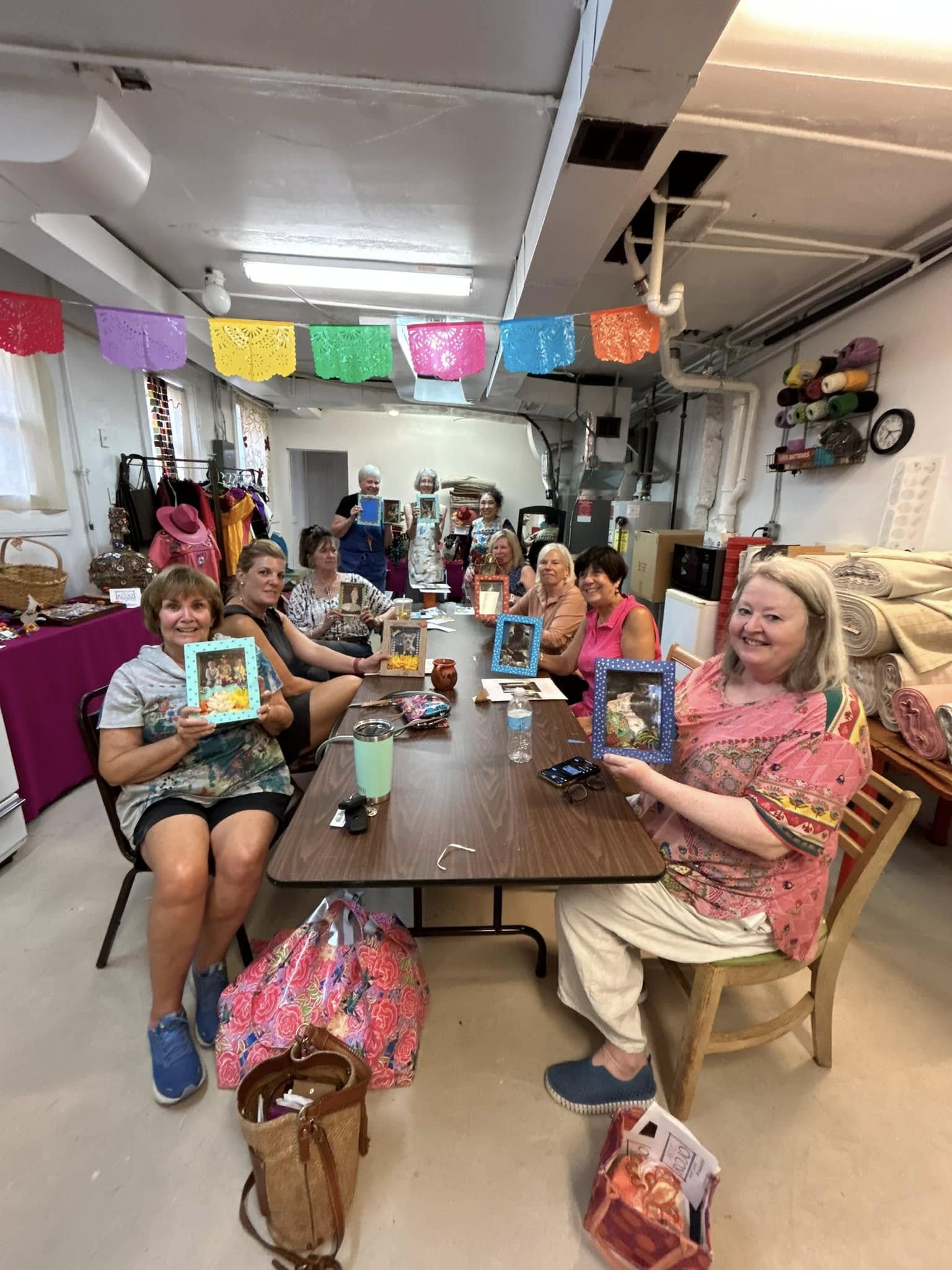 Children sitting around a table in a decorated room, holding tablets, with colorful banners overhead.