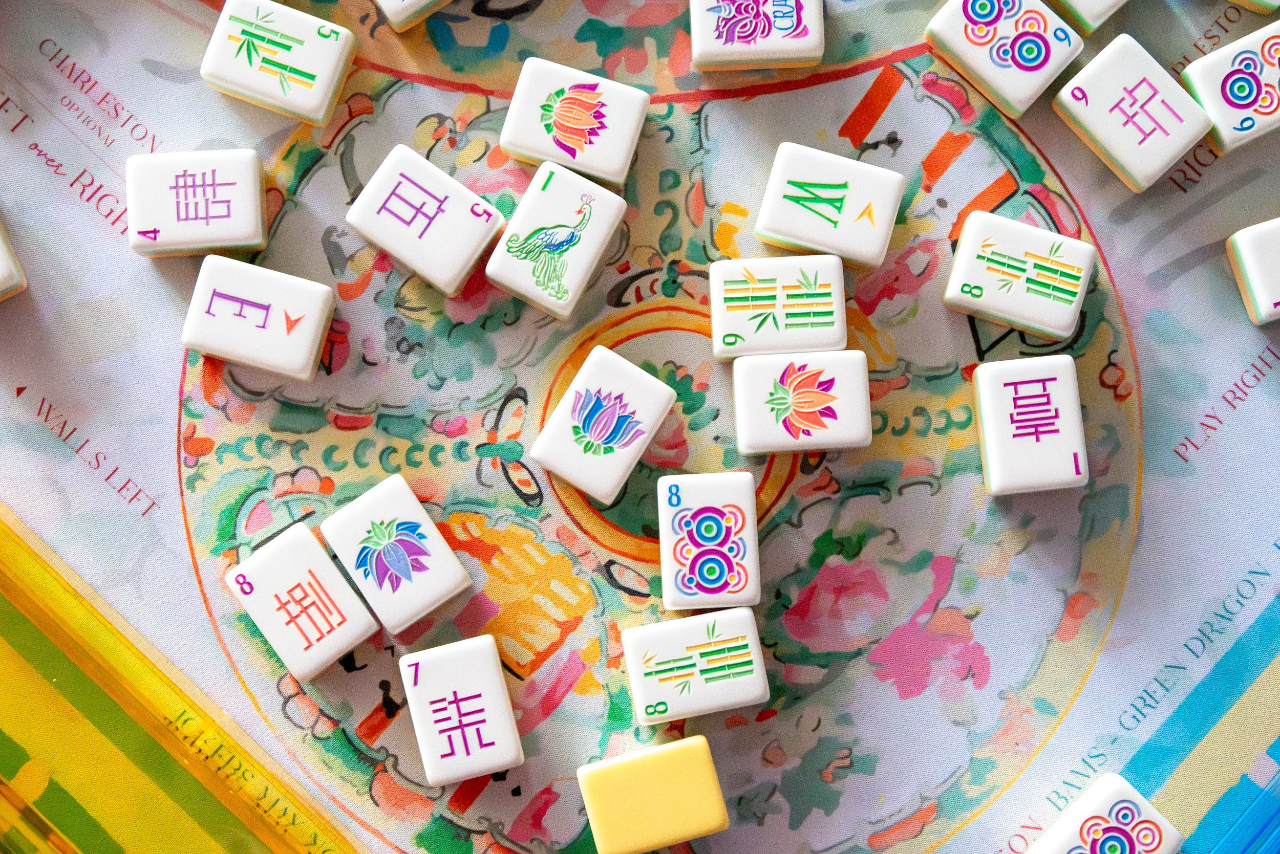 Colorful Mahjong tiles scattered on a paper with a heart-shaped design, some tiles showing symbols and characters.