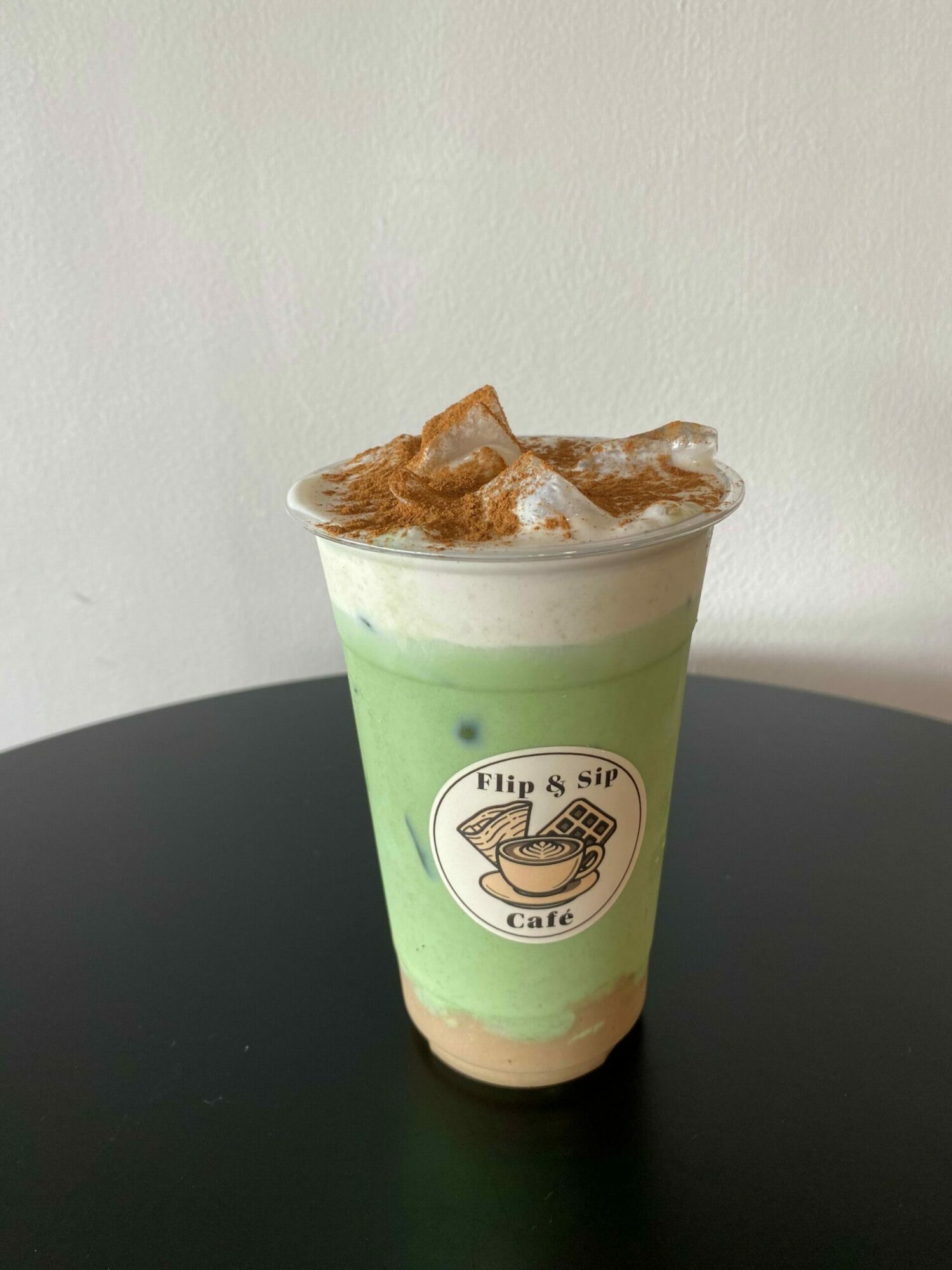 A partially eaten ice cream in a green cup with a logo, on a black surface, against a light background.