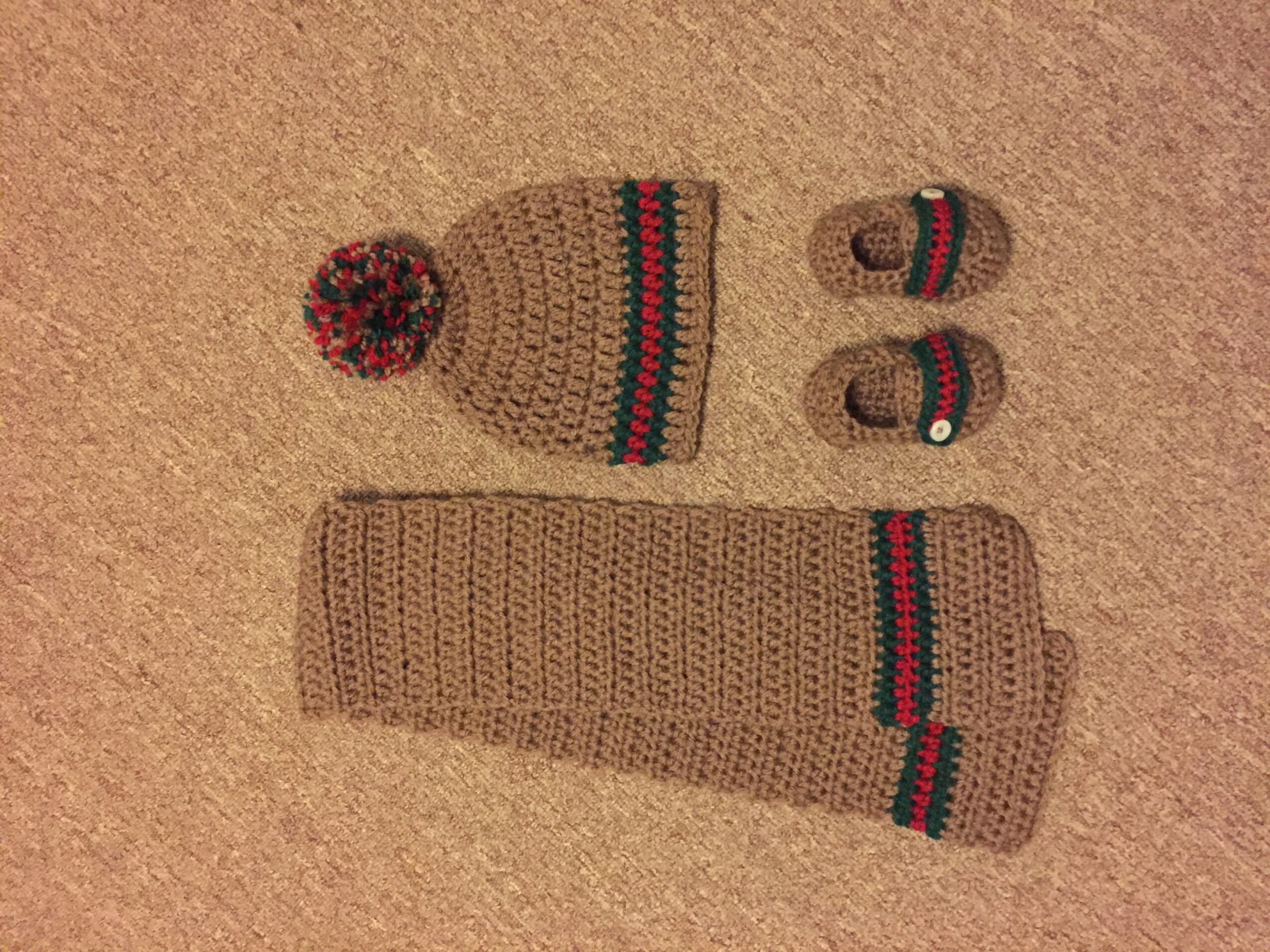 Set of knitted winter accessories including a hat with pom-pom, mittens, and a scarf, all with striped patterns, on a beige background.