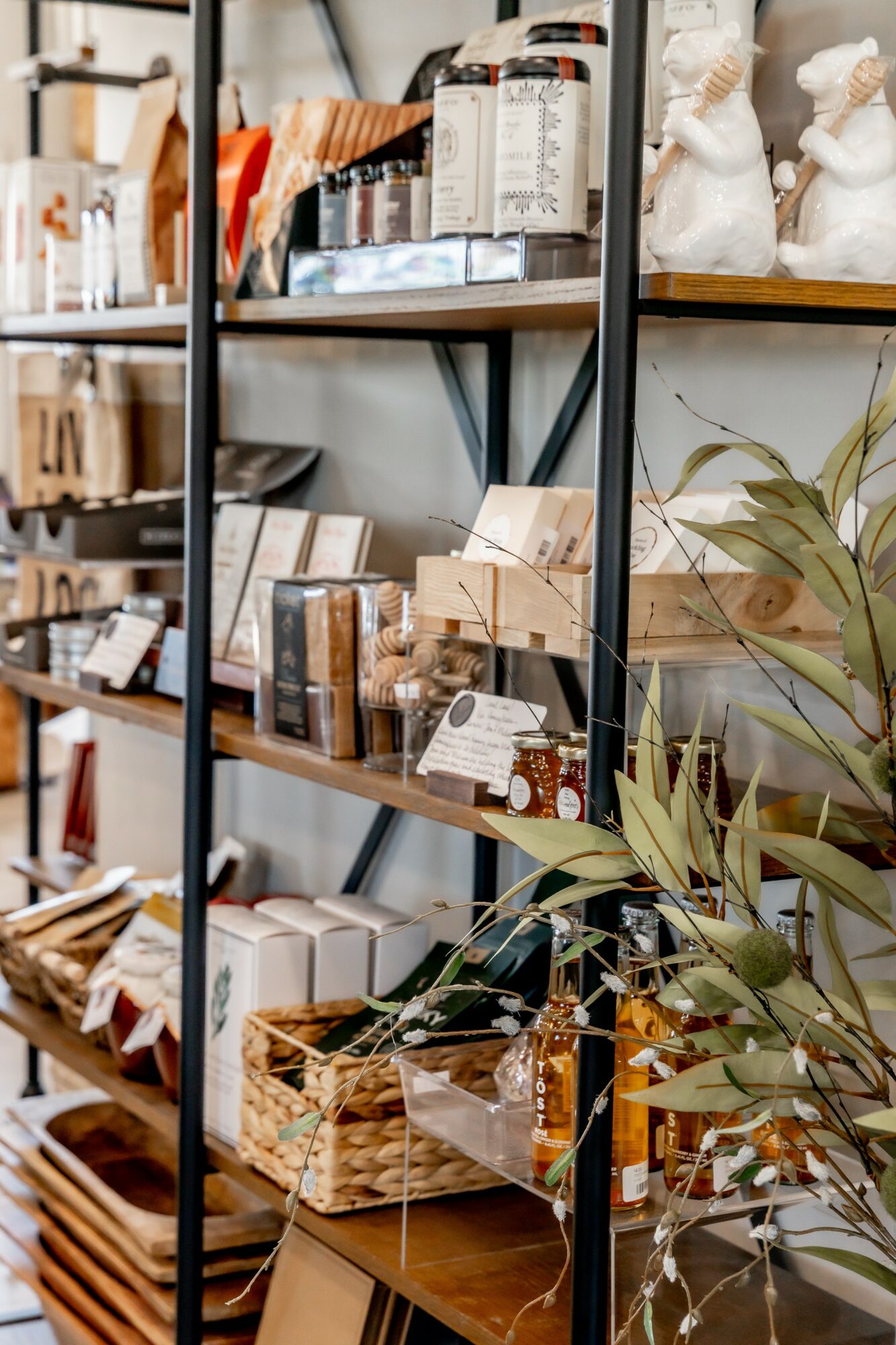 Shelves filled with various home decor items, plants, and baskets in a store or display setting.
