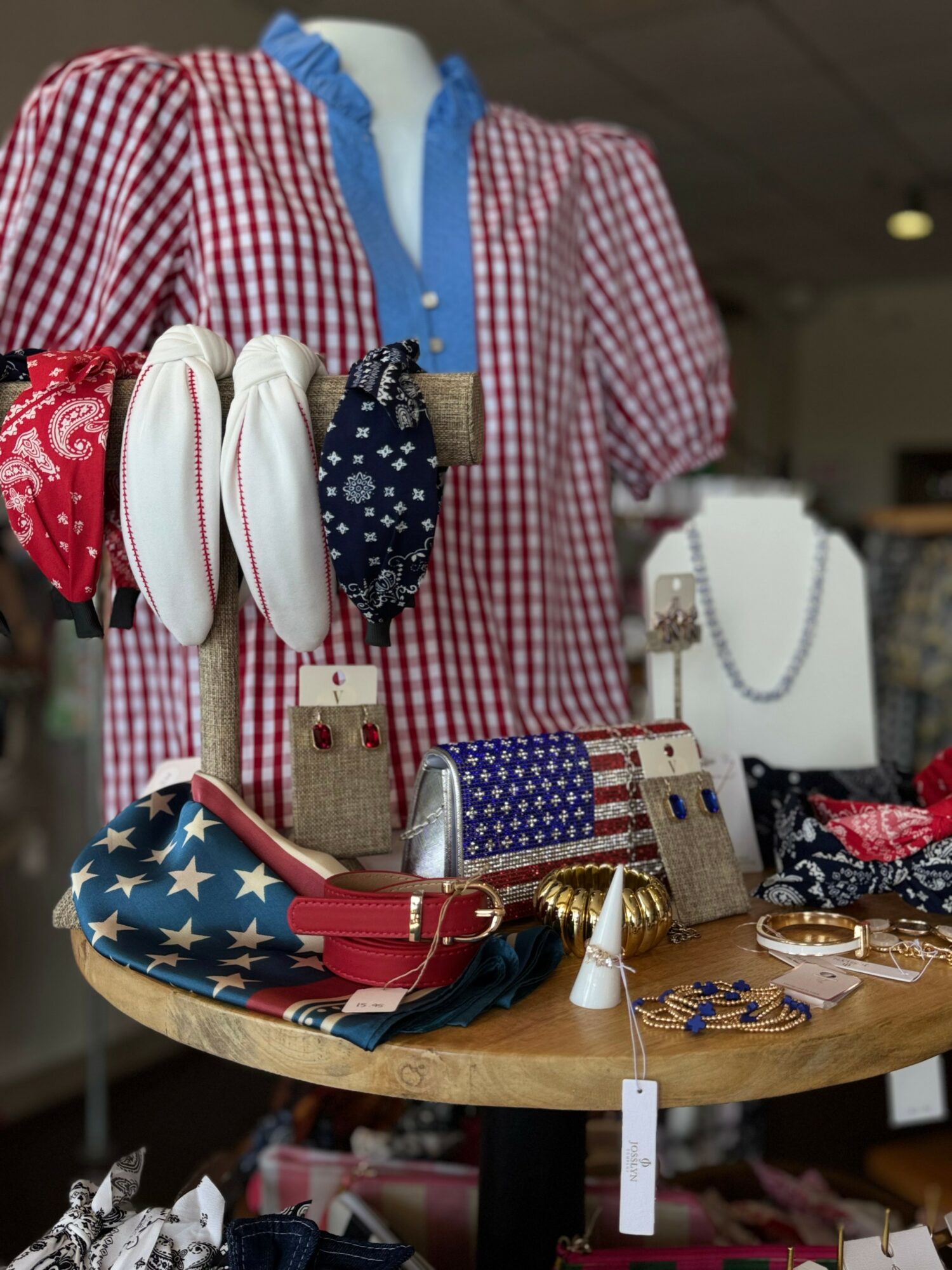 Display of jewelry and accessories with a red and white checkered shirt in the background.