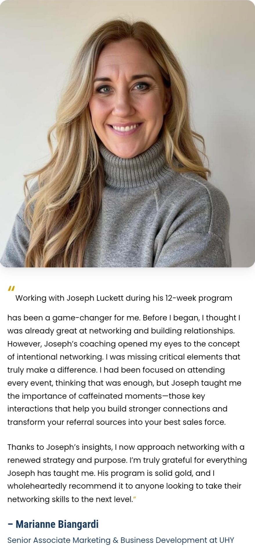 Portrait of a smiling woman with long blonde hair wearing a gray turtleneck sweater, against a plain background.