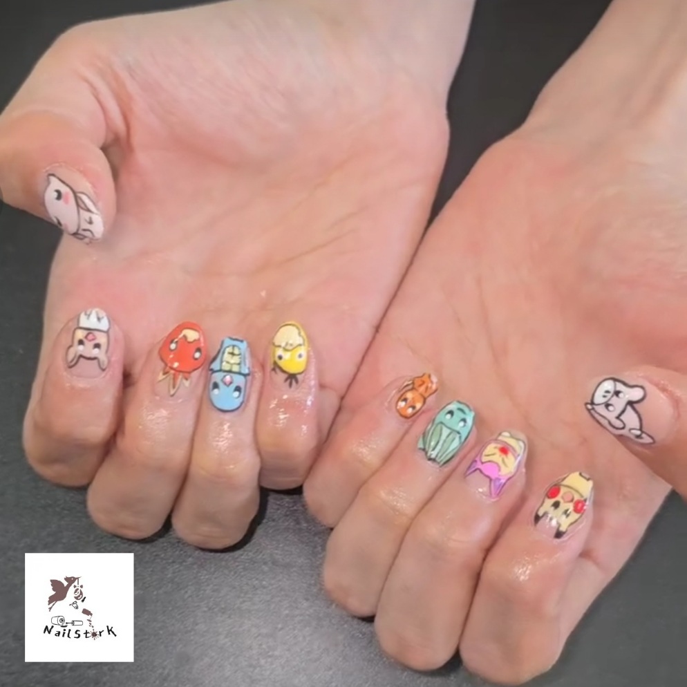 Hands with colorful cartoon character nail art, including animals and faces, on fingers and thumbs, against a dark background.