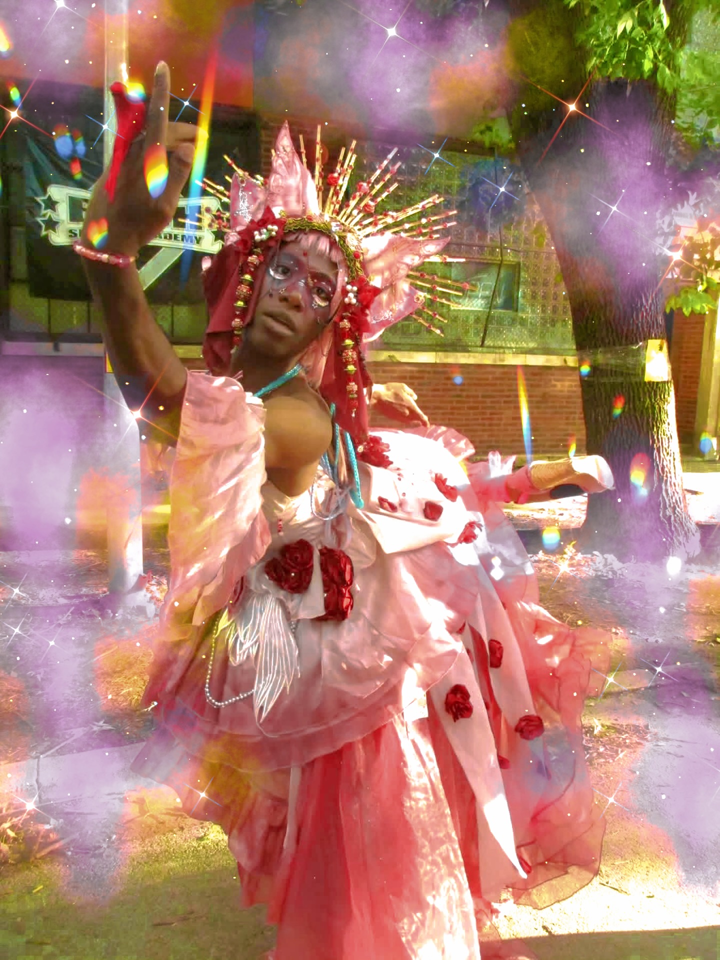 Child dressed in pink costume with a crown, surrounded by colorful smoke and lights outdoors.