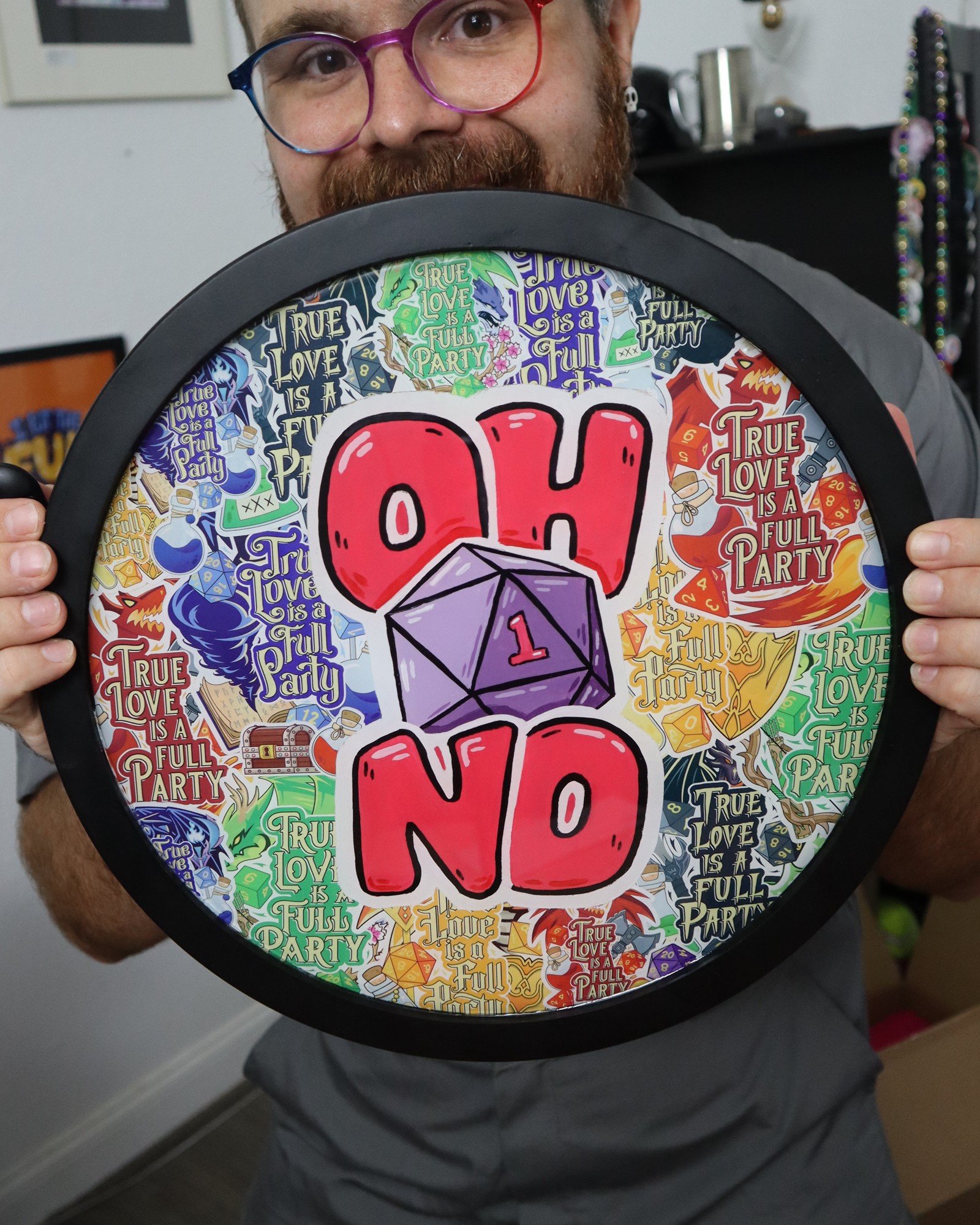 Person holding a circular sign with colorful background, large red and purple text reading