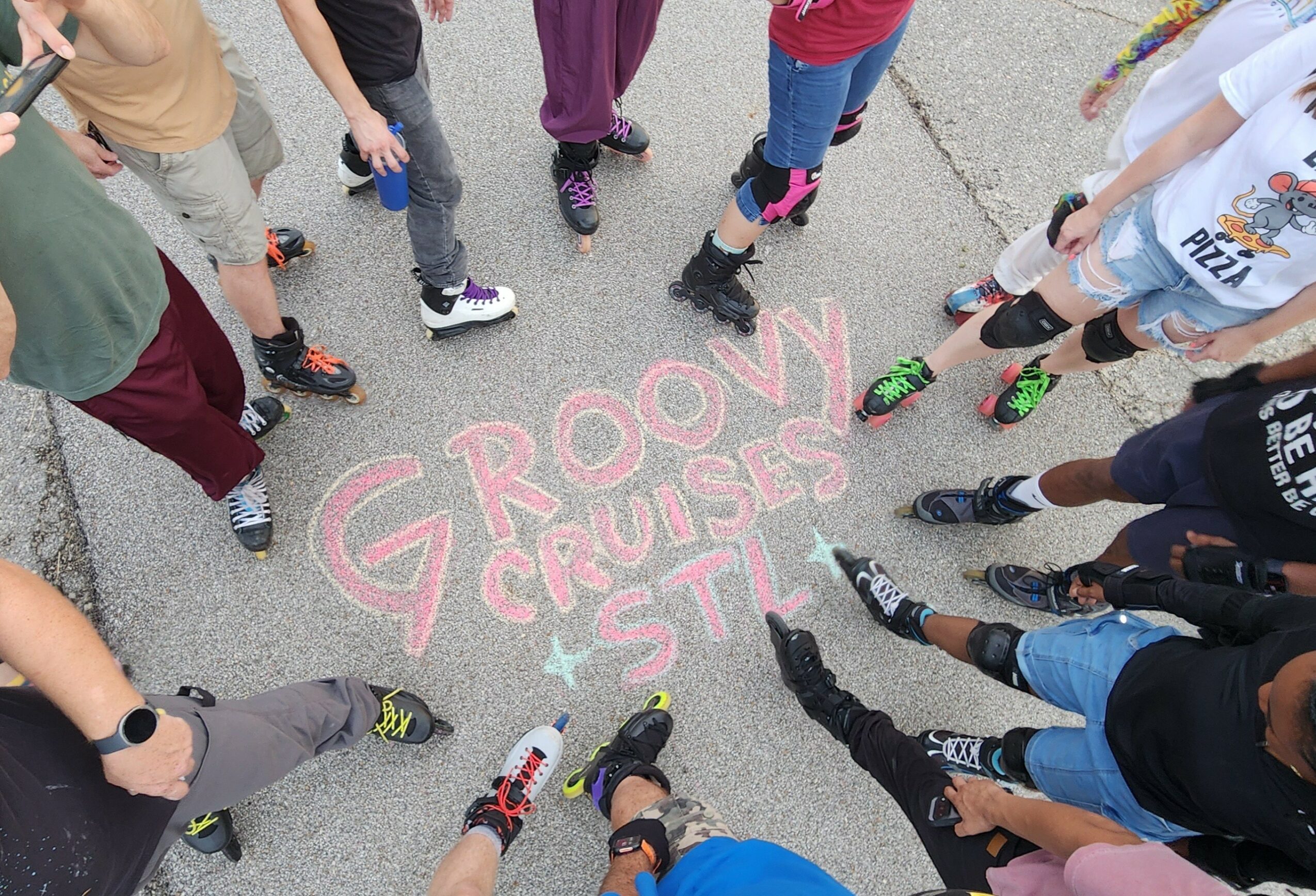 Group of children standing in a circle around colorful chalk writing on pavement, reading 'Groovy Cruise Style'.