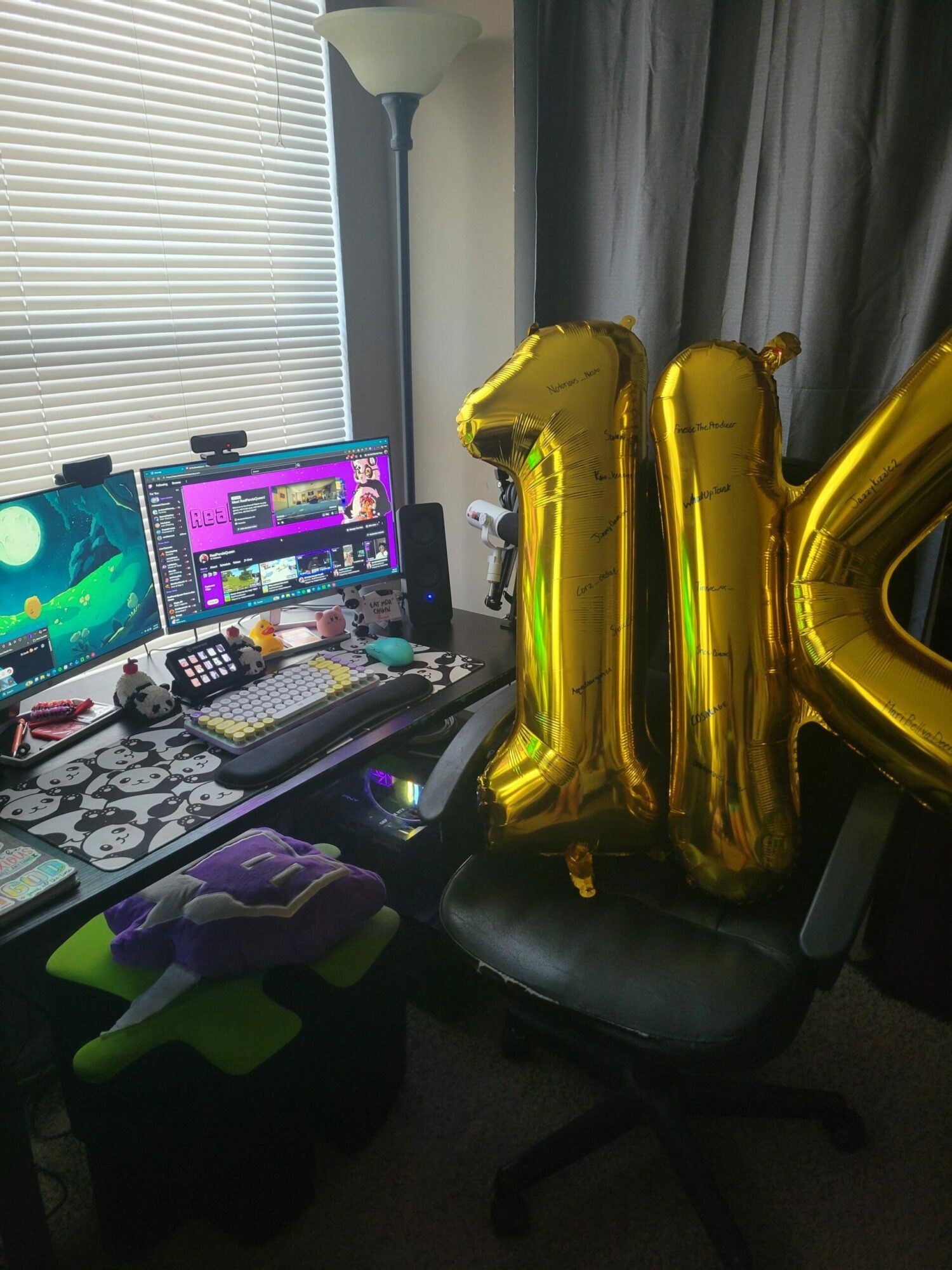 Desk with two monitors, keyboard, mouse, and a laptop, with gold balloon letters in the background.
