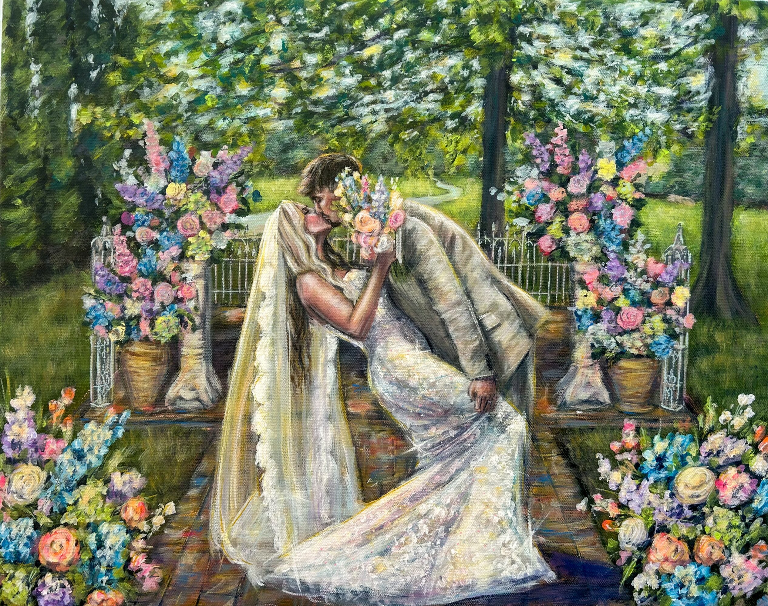 A bride and groom kiss outdoors with floral arrangements and trees in the background.