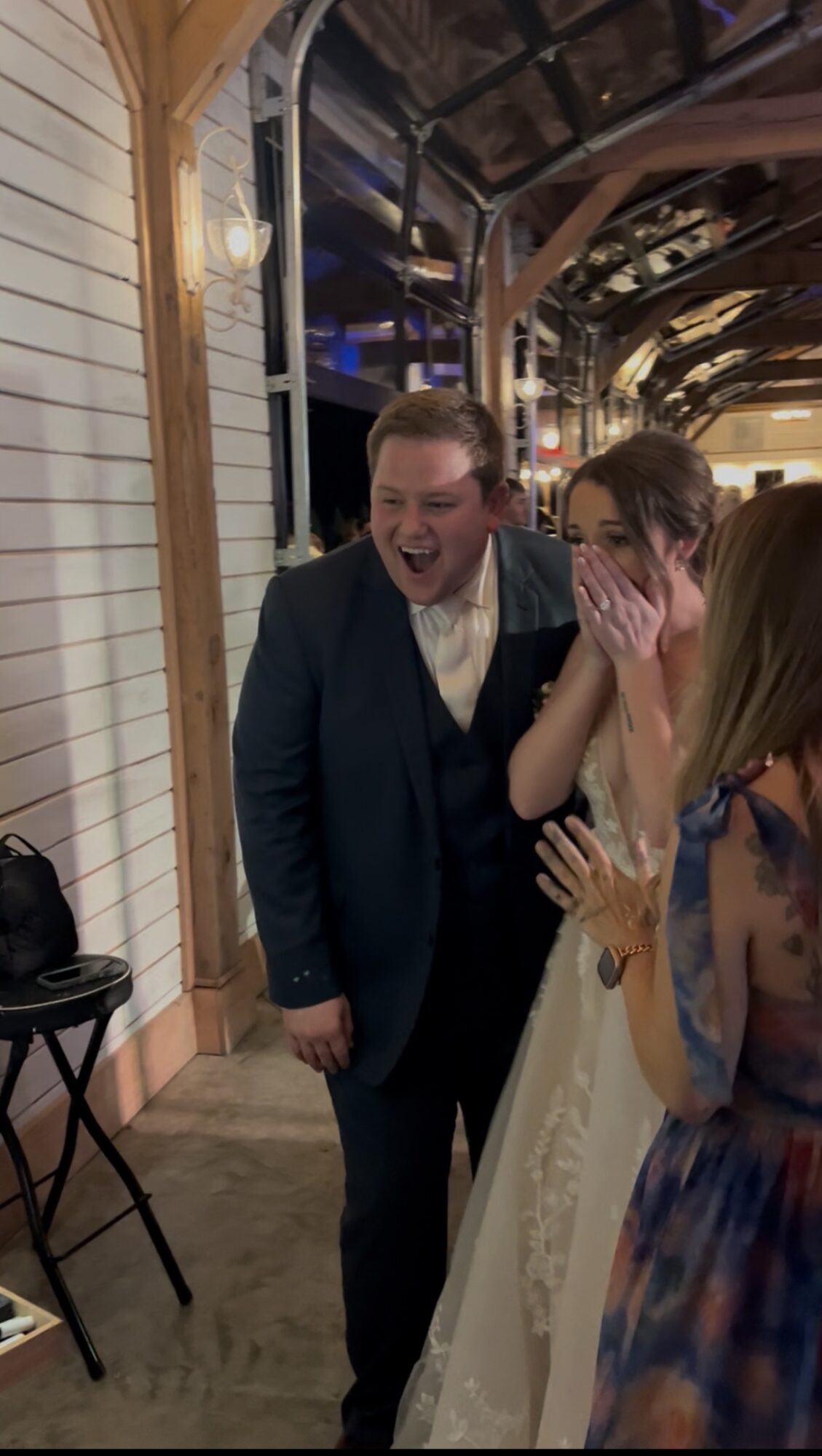 People laughing and talking indoors at a social event, with wooden walls and decorative lighting.